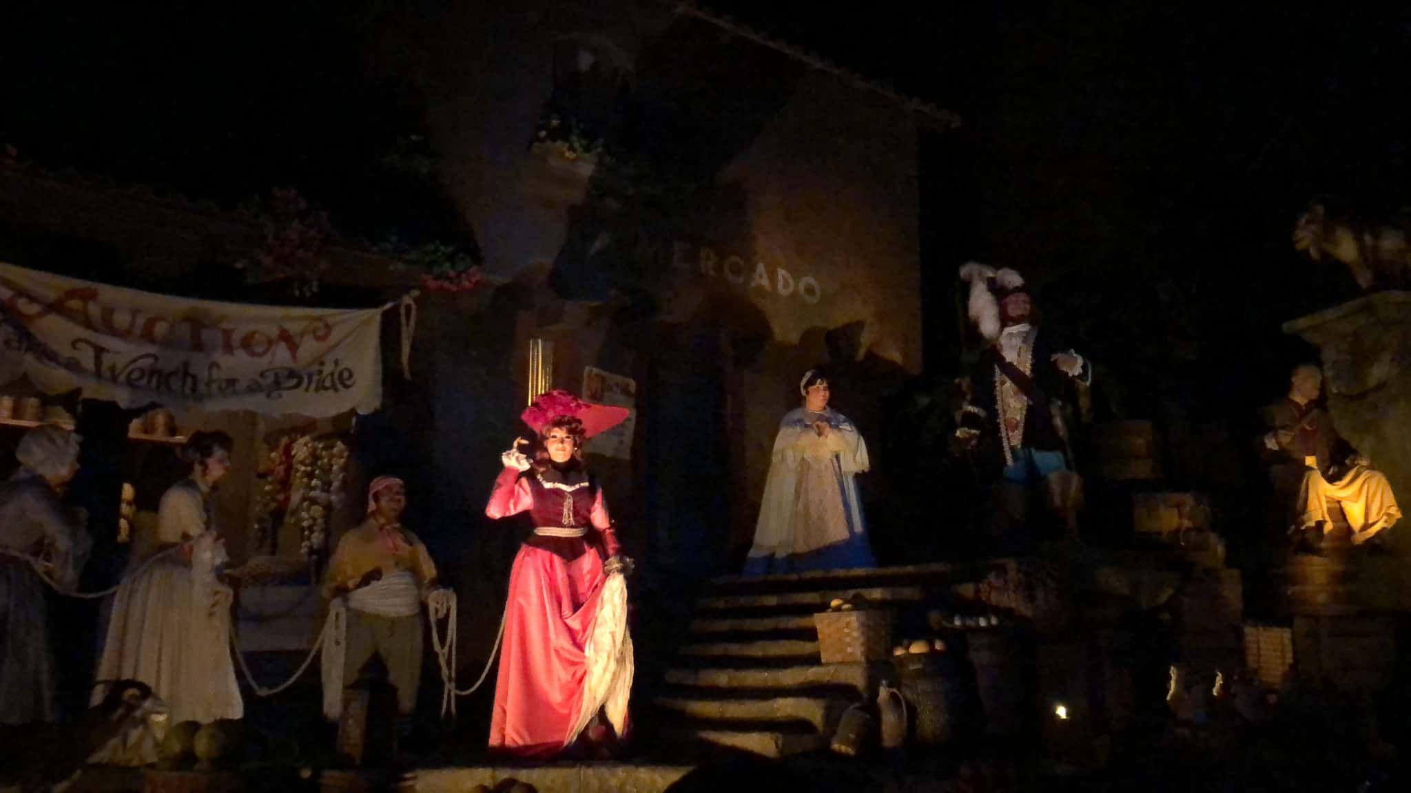 Animatronic figures highlight a nighttime auction scene in the Pirates of the Caribbean ride at Disneyland.