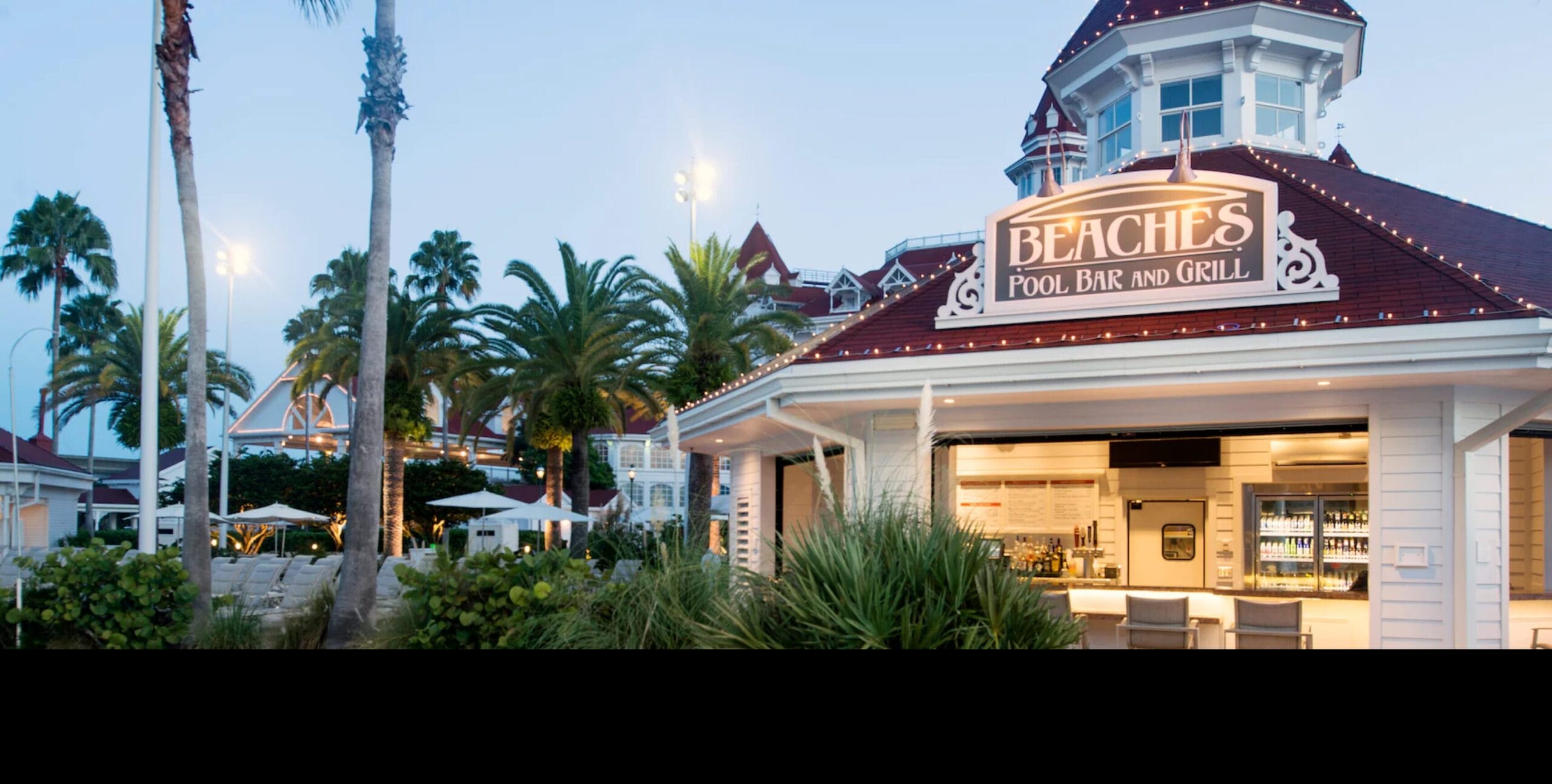 Beaches Pool Bar and Grill offers outdoor seating under palm trees and umbrellas near the resort at dusk.
