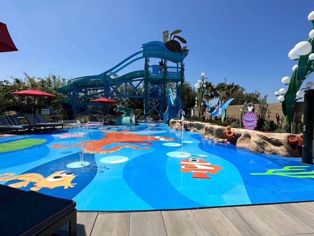 Experience the newly refurbished children's splash pad at Pixar Place Hotel, featuring aquatic-themed designs, a large water slide, and playful water jets. Relax under surrounding umbrellas on the sunny pool deck while your little ones make a splash.