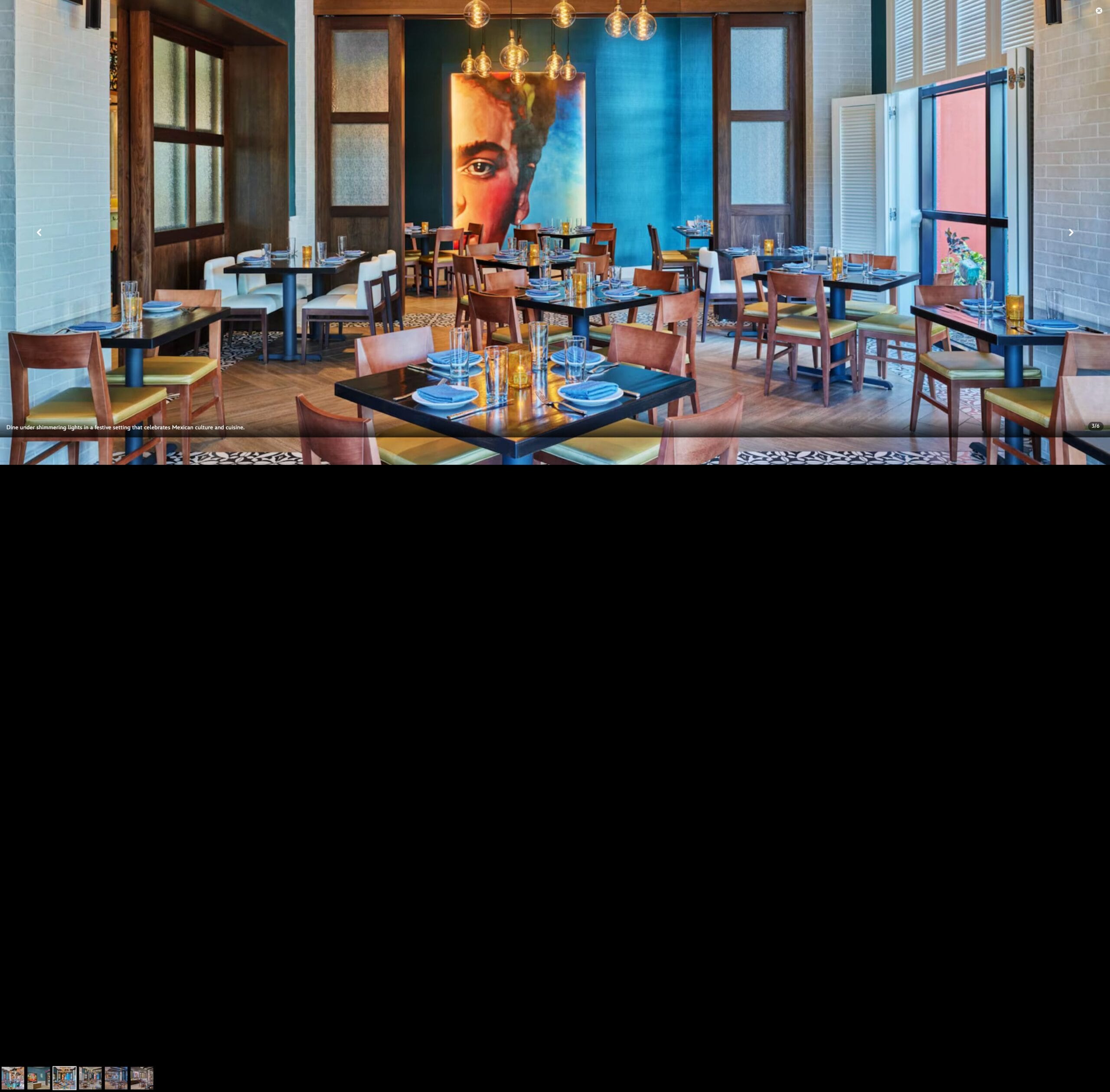 Bright, modern Rosa Mexicano restaurant with wooden tables and a large mural of a woman's face on a blue wall.