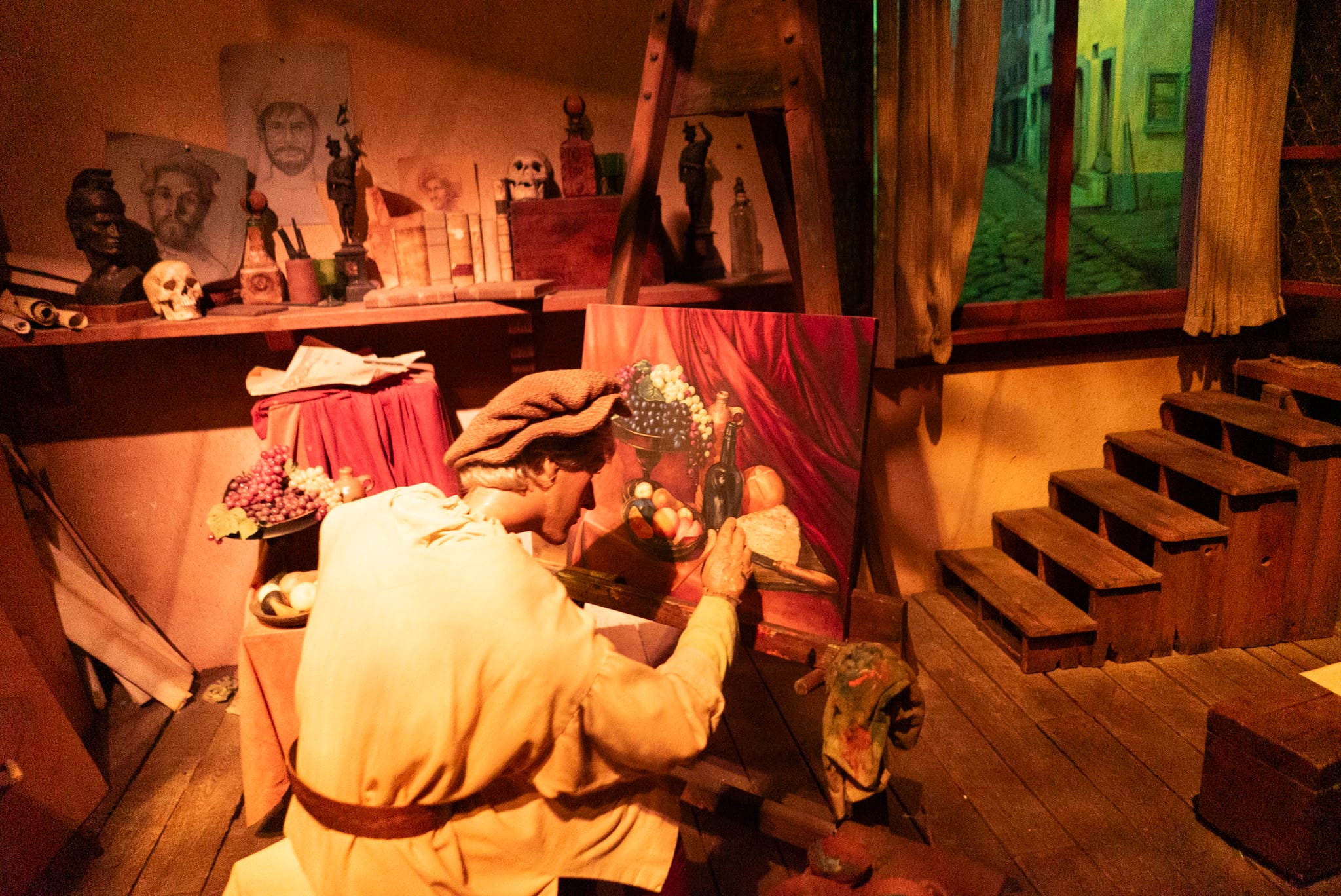 An artist in historical clothing paints a still life in a rustic studio, reminiscent of EPCOT’s Spaceship Earth scenes.