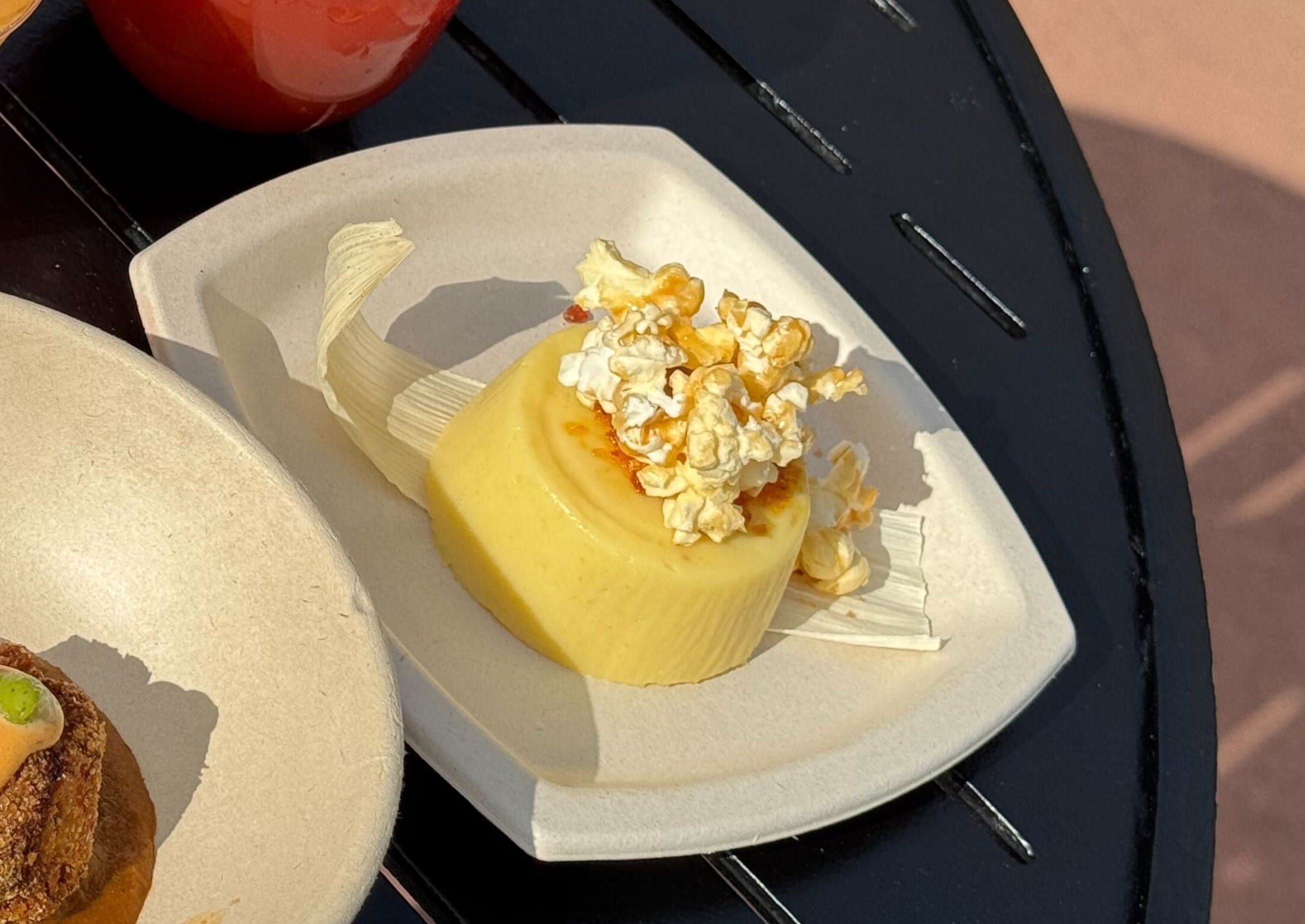 A dessert on a plate adorned with popcorn and caramel sauce, capturing the spirit of the Festival of the Arts, served elegantly on a black table.