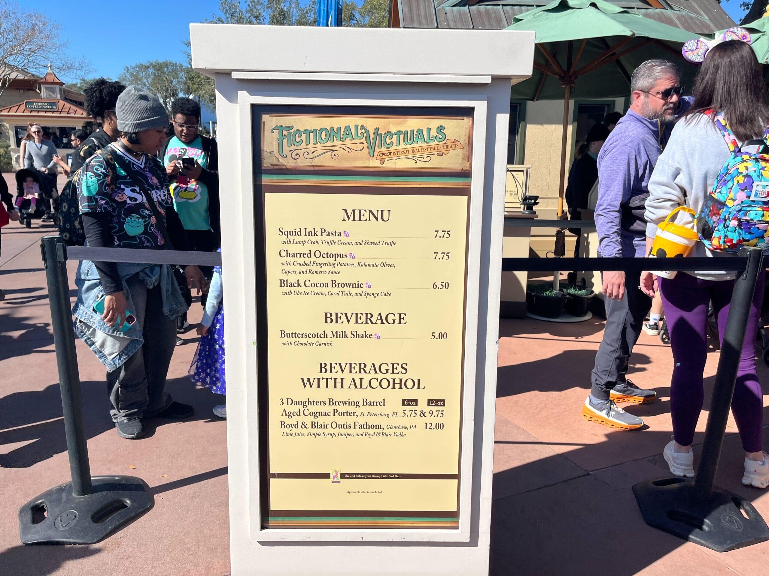 The menu sign titled "Fictional Nectuals" entices with gourmet delights like squid ink pasta and charred octopus, each dish a masterpiece reminiscent of the Festival of the Arts. Delight in our exceptional alcoholic options to complete your artistic culinary journey.