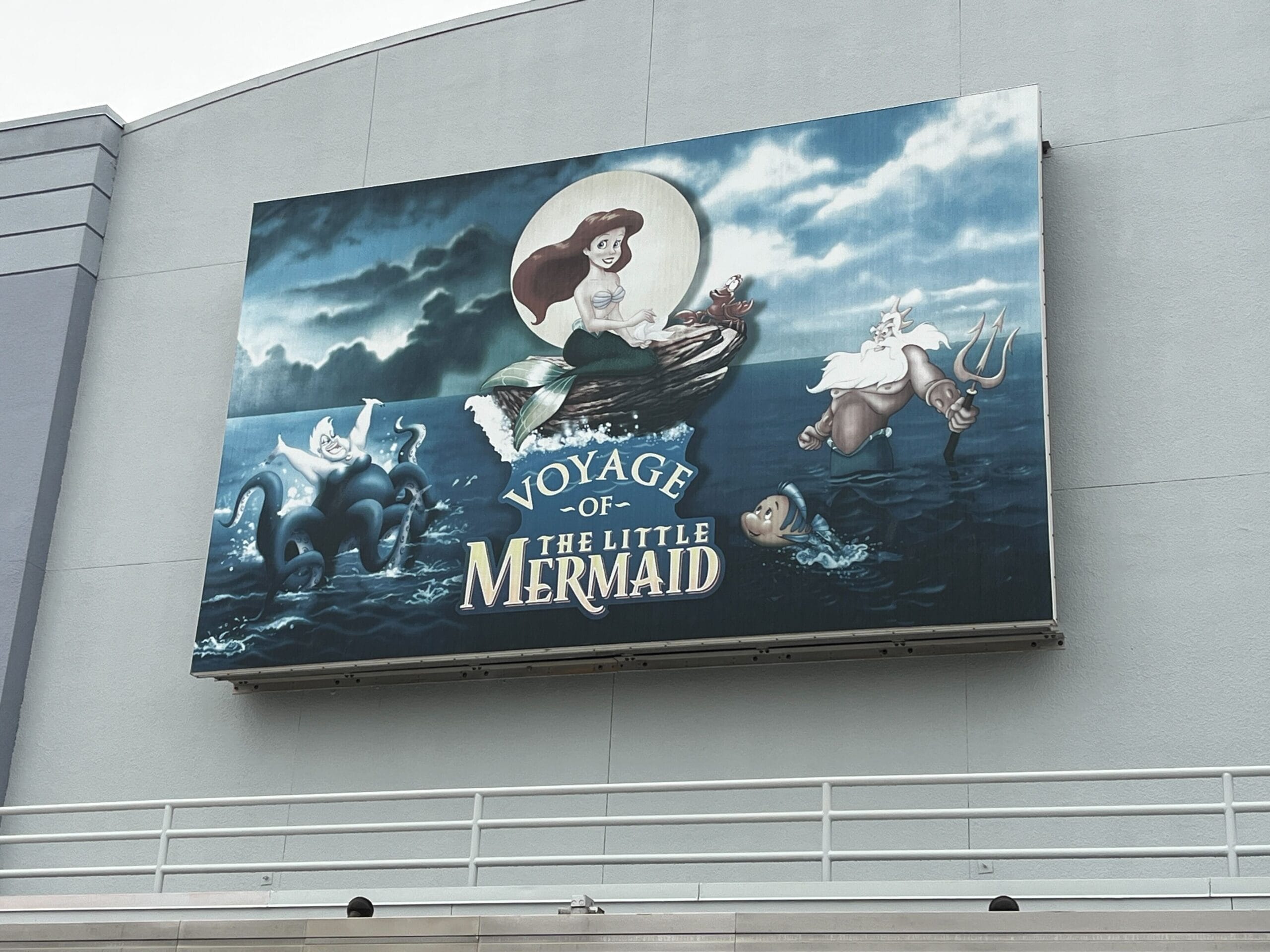 A large mural on the wall serves as a vibrant marquee, showcasing Ariel, Flounder, and King Triton from "The Little Mermaid," accompanied by the text "Voyage of the Little Mermaid.