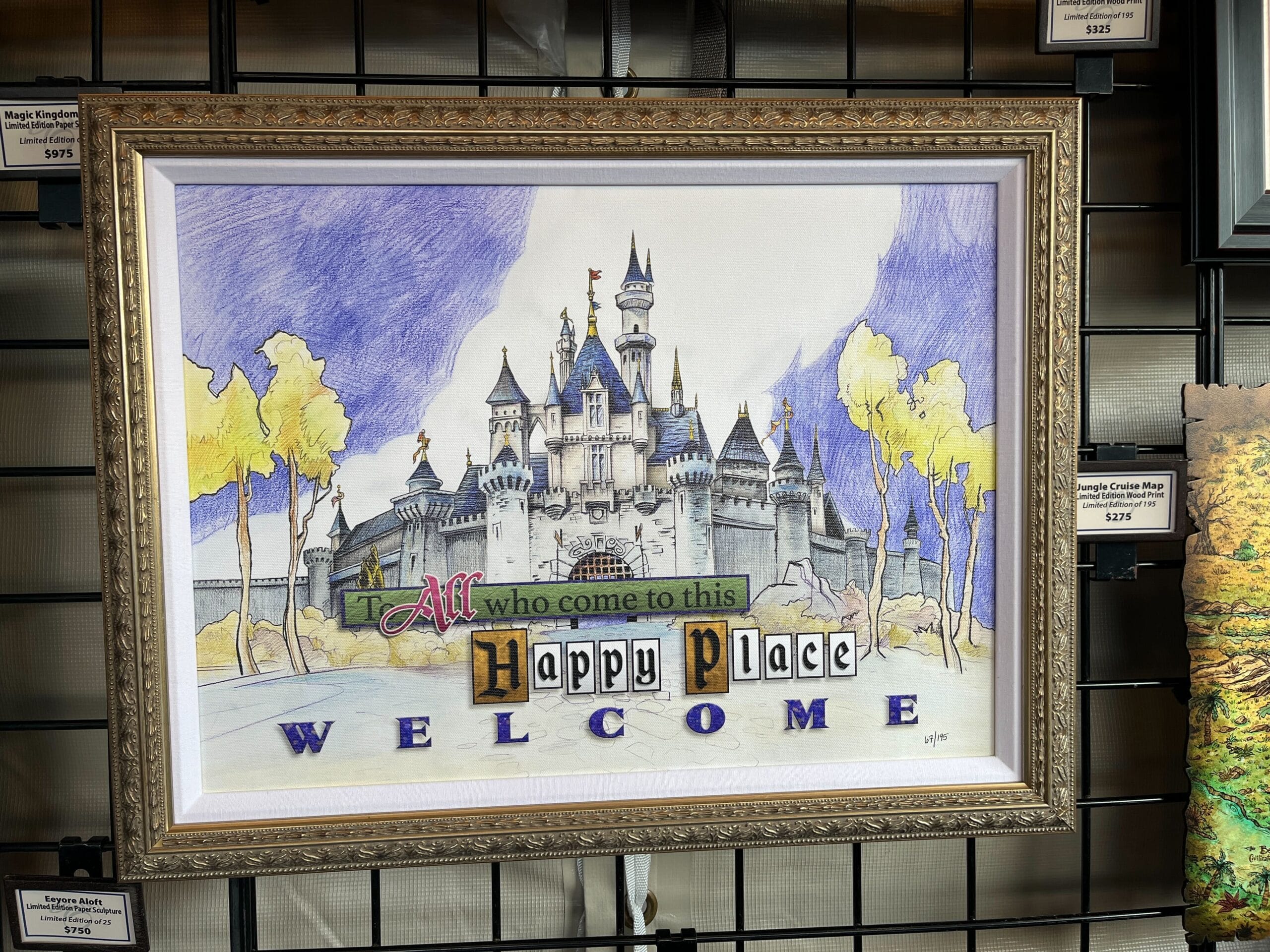 Framed artwork of a fantasy castle with the words "To all who come to this happy place, welcome" below, reminiscent of the enchanting displays seen at the EPCOT Festival of the Arts.