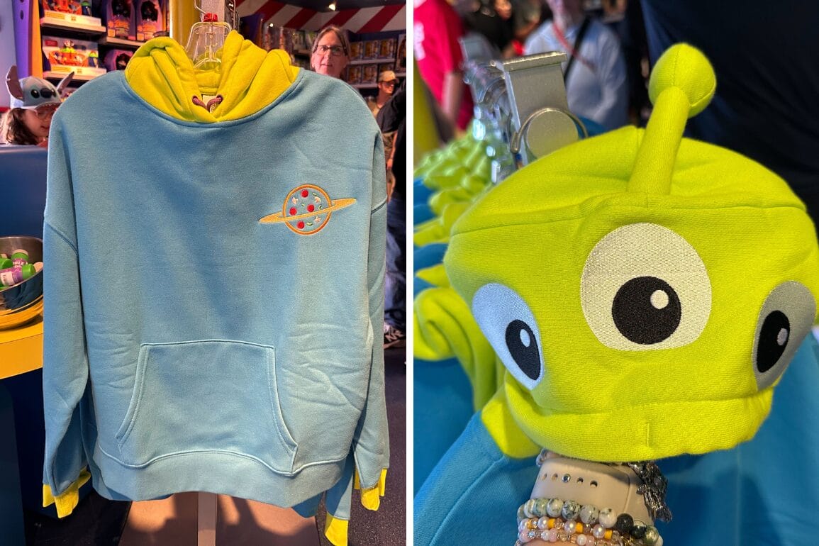 Side-by-side images of a blue hoodie with a yellow planet design, and a green alien-themed hat with large eyes and antennas on display in a store.