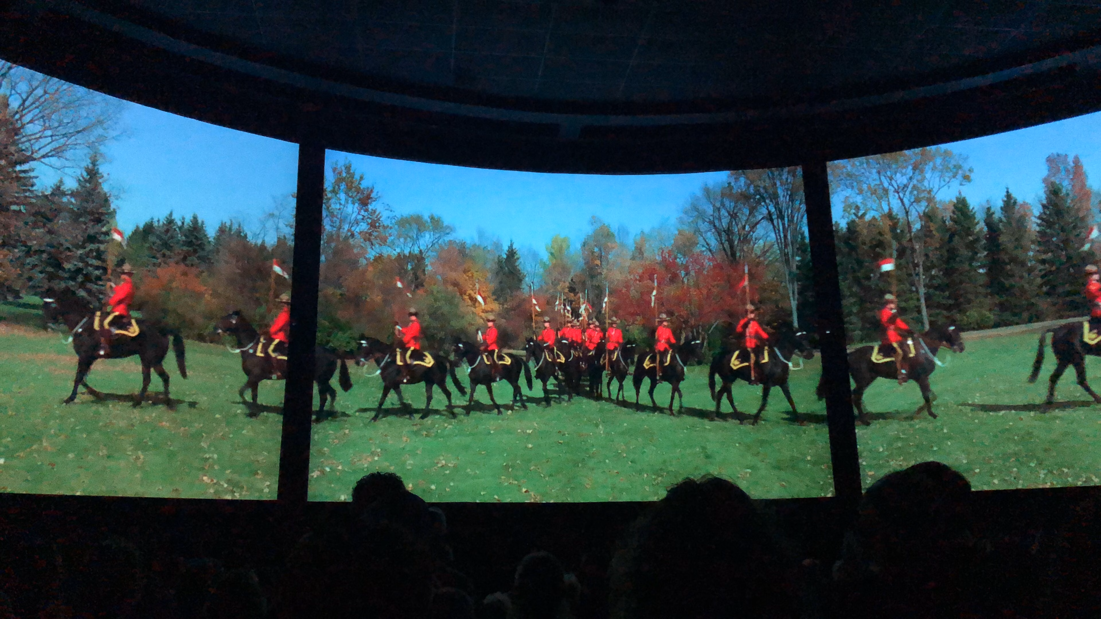 A curved Circle-Vision 360 screen shows horse riders in red uniforms on green grass, watched by an audience.