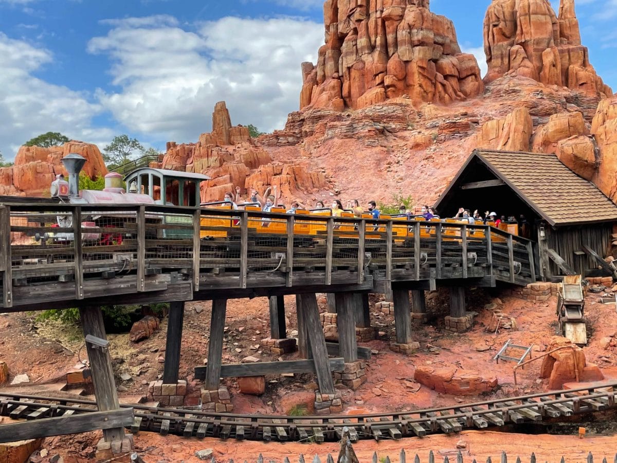 A runaway mine train roller coaster, Big Thunder Mountain Railroad, races through red rock canyons under the Disneyland sky.