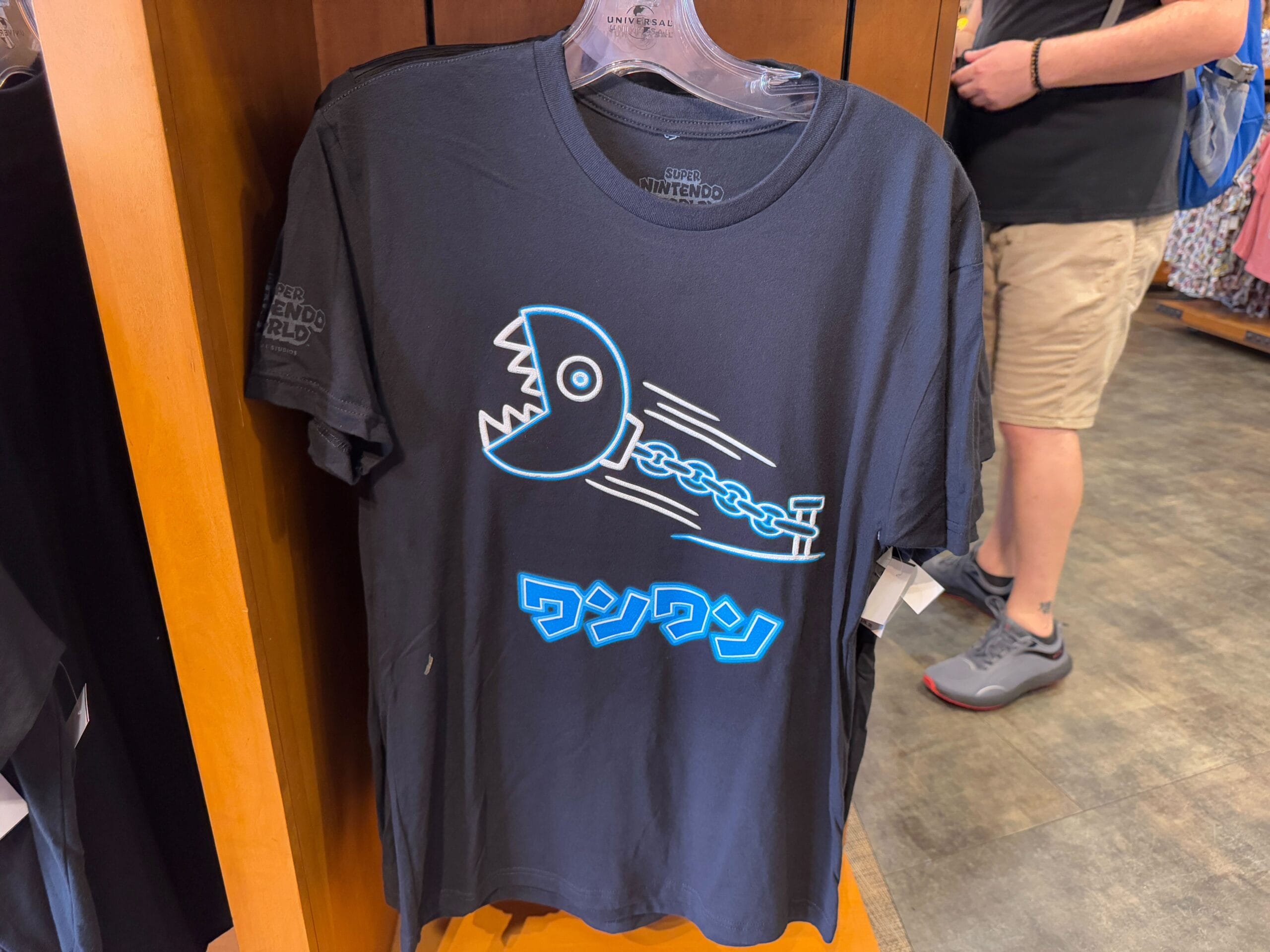 Black t-shirt with a blue chain chomp graphic and Japanese text on a store display, part of the Epic Universe Merchandise at Universal Studios Florida.
