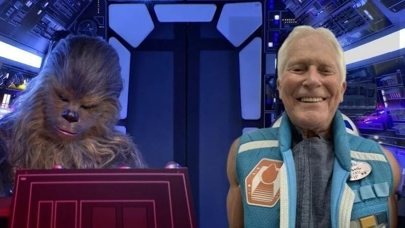 A person smiles beside a Chewbacca character in a sci-fi themed setting, with futuristic controls and lighting, reminiscent of Phil Bailey's imaginative universe.