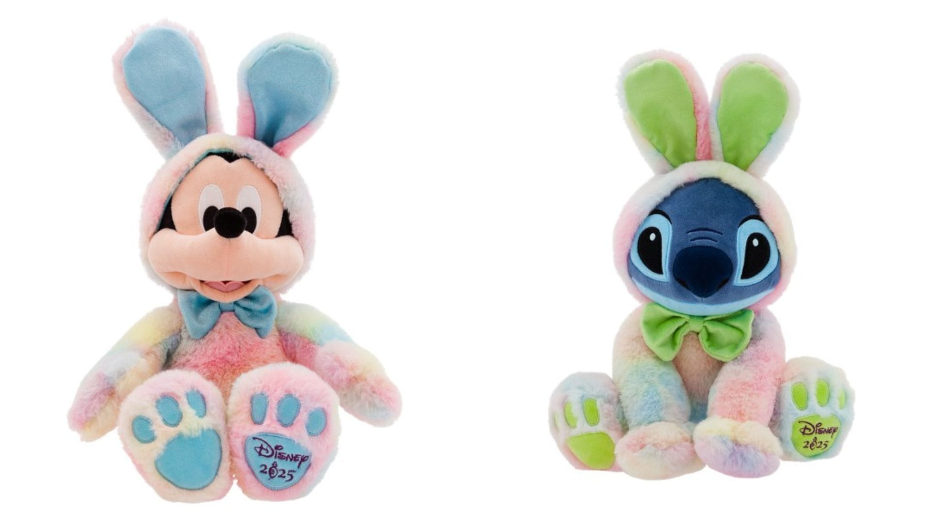 Two plush toy figures wearing pastel rainbow bunny costumes, featuring Mickey Mouse and Stitch, each with a bow tie and embroidered "Disney 2023" on their feet.