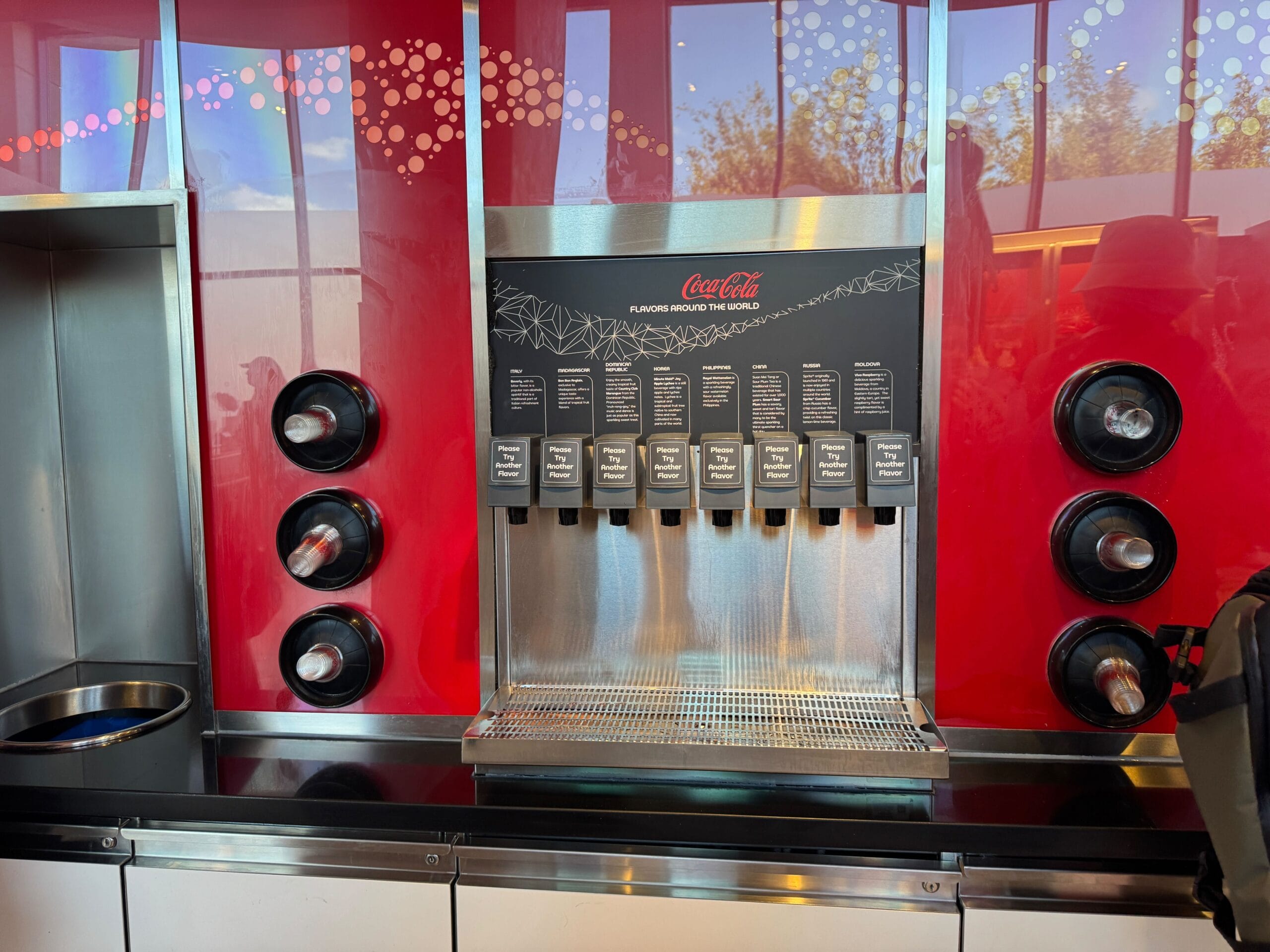 A Coca-Cola beverage dispenser with multiple drink options against a red background.
