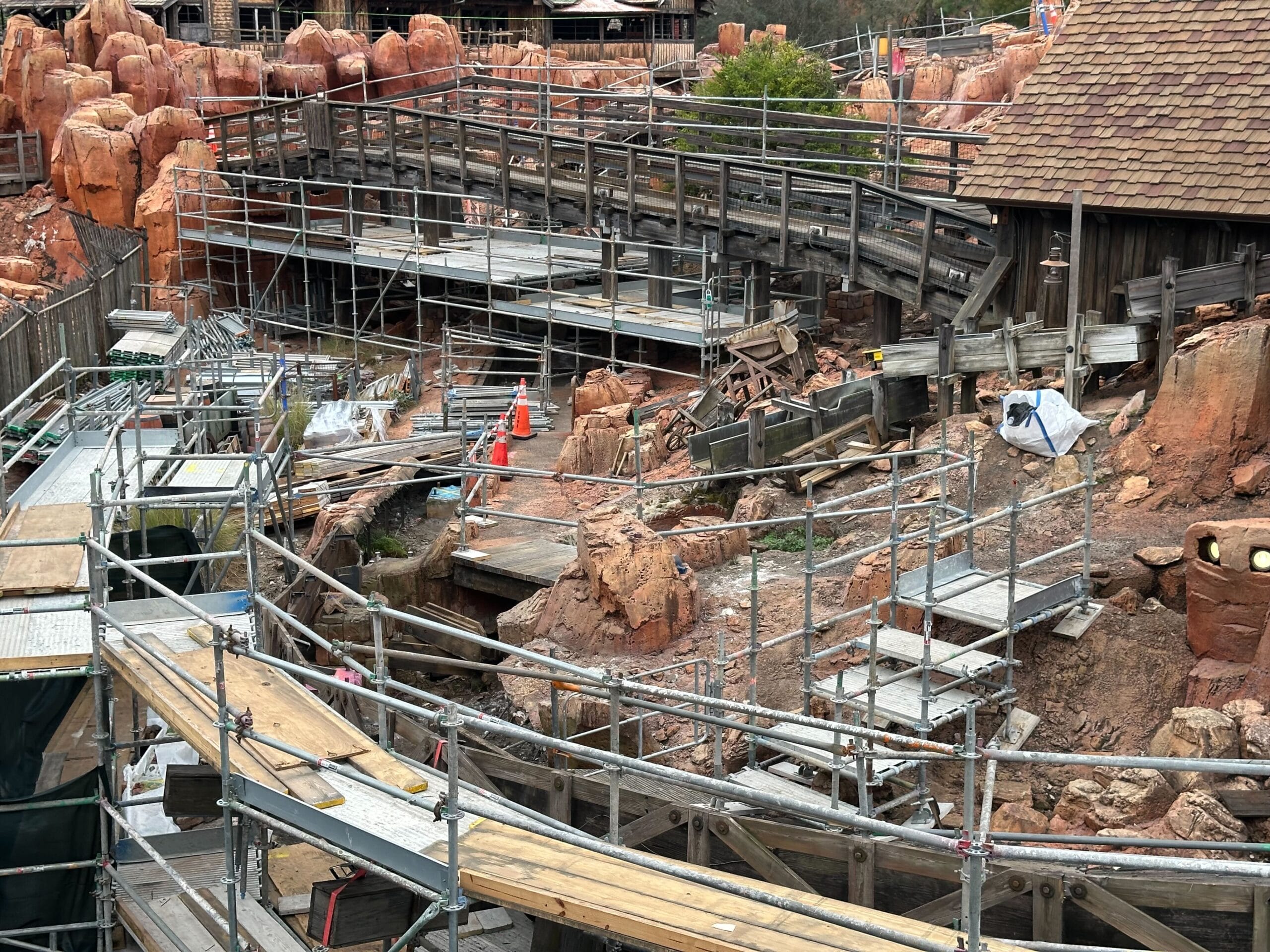 A construction site with scaffolding and wooden walkways surrounds the rugged terrain, reminiscent of Thunder Mountain.