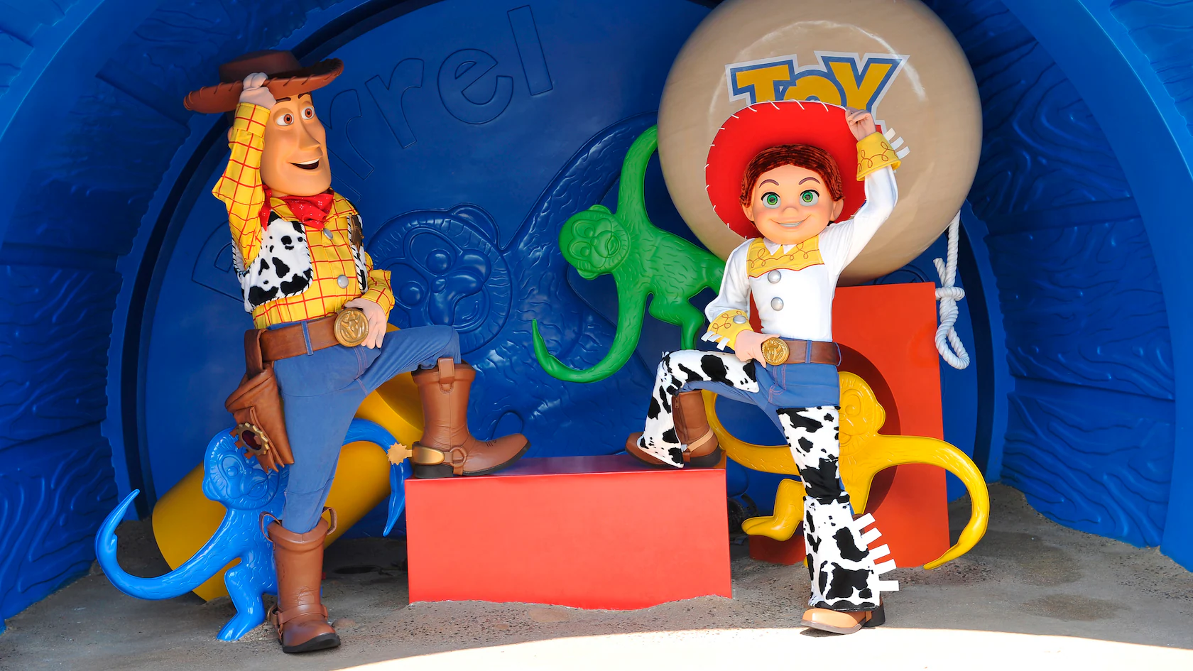 Statues of two cowboy characters with a western theme, surrounded by colorful toy animals and a large ball with a "Toy" logo in the background, create a true Barrel of Fun.