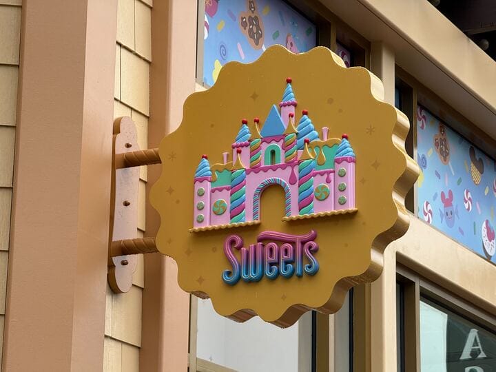 A hanging sign with a colorful castle and the words "Wonderful World of Sweets" adorns the building's exterior, decorated with playful designs.