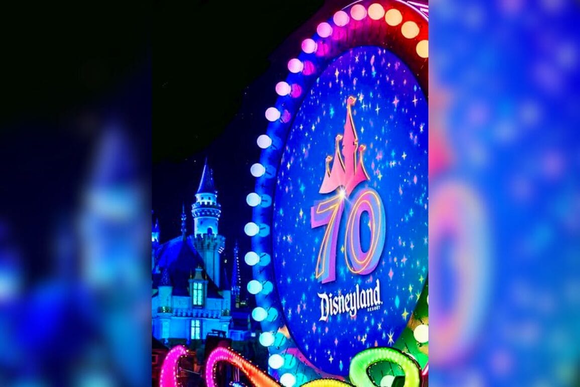 A vibrant sign celebrating Disneyland's 70th anniversary showcases a castle silhouette, surrounded by twinkling lights and a starry sky, reminiscent of the enchanting "Paint the Night" parade.