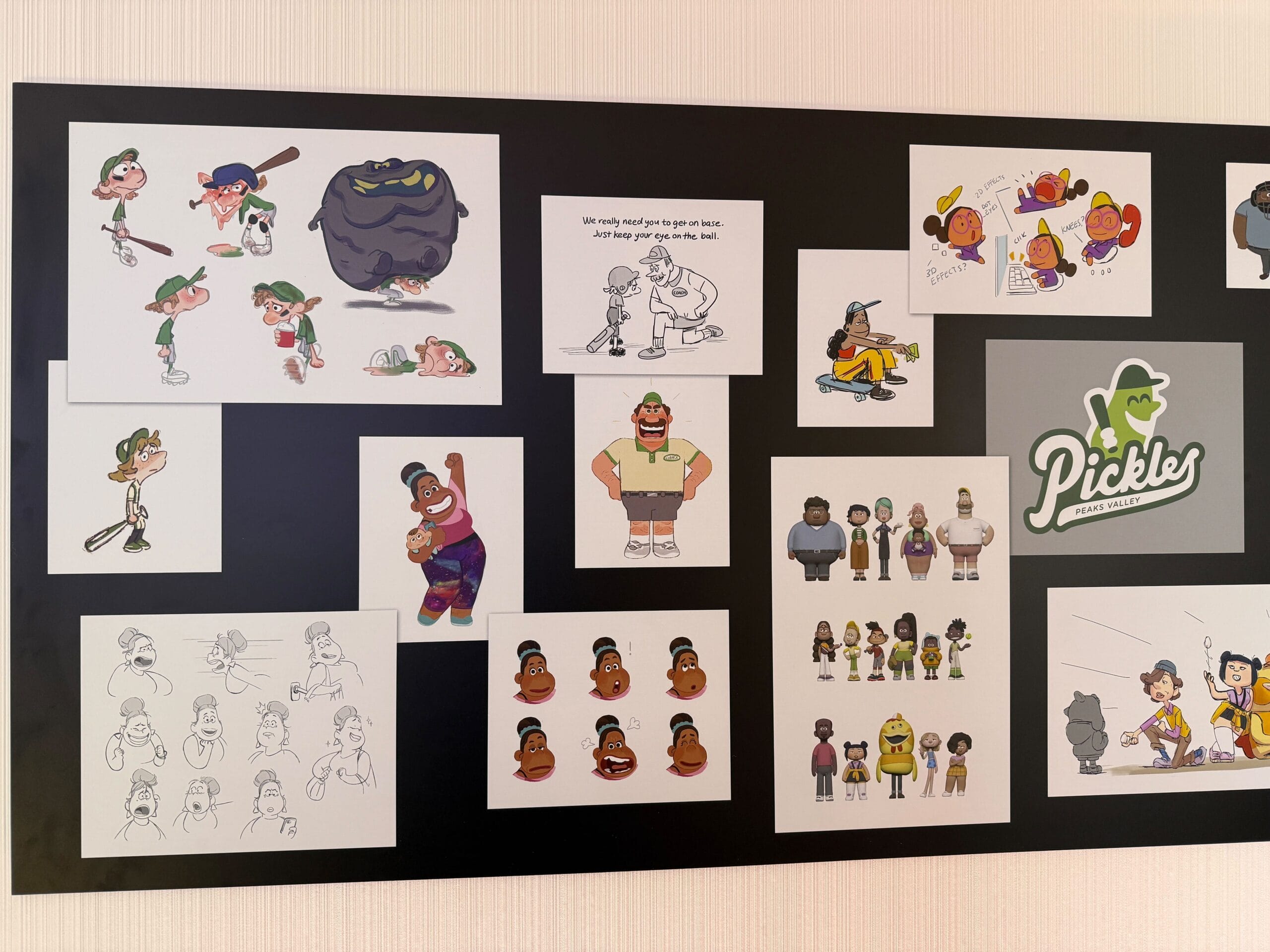 A wall display at the Pixar Place Hotel showcases a vibrant array of cartoon character sketches and colored illustrations, featuring diverse figures with a playful "Pickles" logo, all part of the Win or Lose Art Exhibit at Disneyland Resort.
