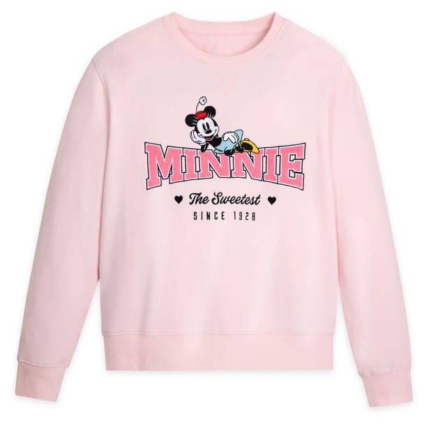 Light pink sweatshirt featuring the word "Minnie" in bold letters, with a character lounging on top and the text "The Sweetest Since 1928" underneath.