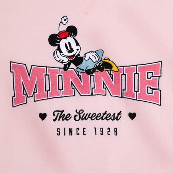 Illustration of Minnie Mouse leaning on the word "Minnie" in pink letters. Below, it reads "The Sweetest Since 1928" with two small black hearts.