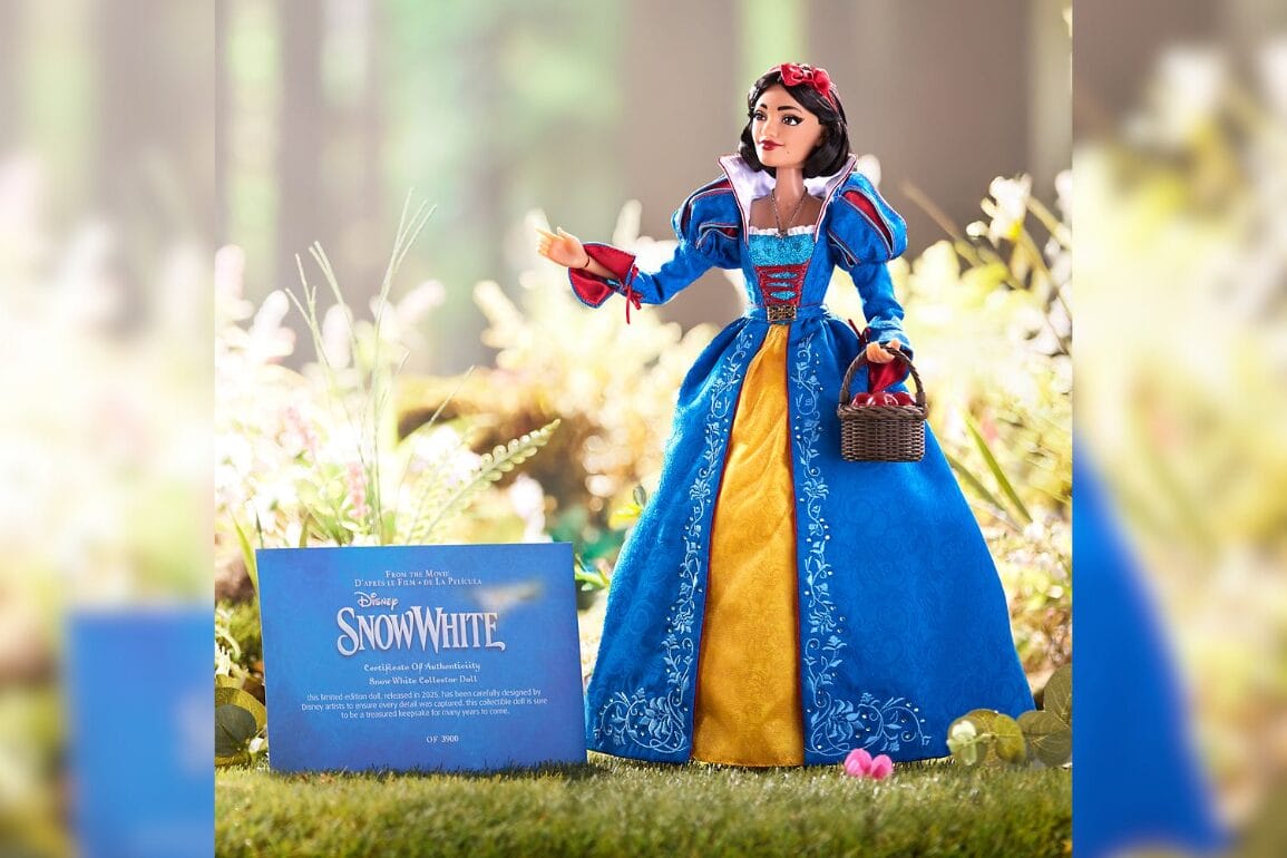 A Snow White doll in a detailed blue and gold gown stands elegantly in the grass, accompanied by its Disney Snow White certificate.