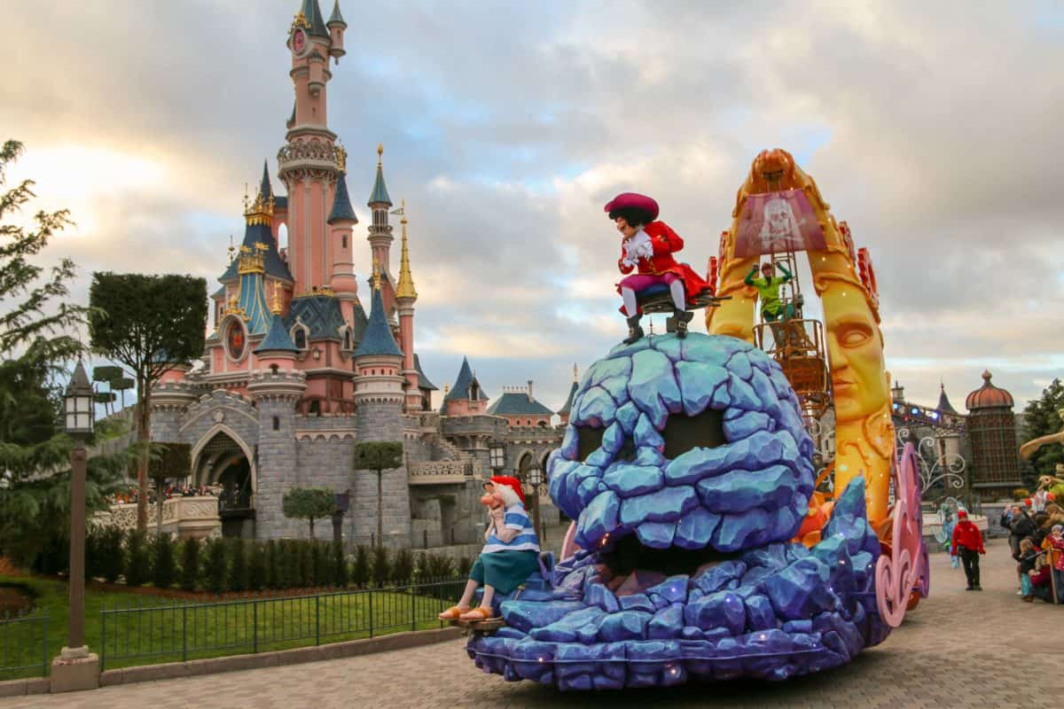 A vibrant parade float featuring beloved characters glides past the enchanting fairytale castle at Disneyland Paris, capturing the magic of the Disney Stars on Parade.