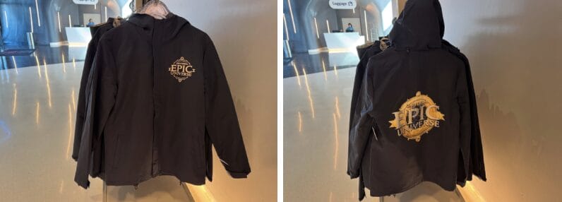 Black rain jackets adorned with the "Epic Universe" logo are displayed on hangers in a well-lit indoor space.
