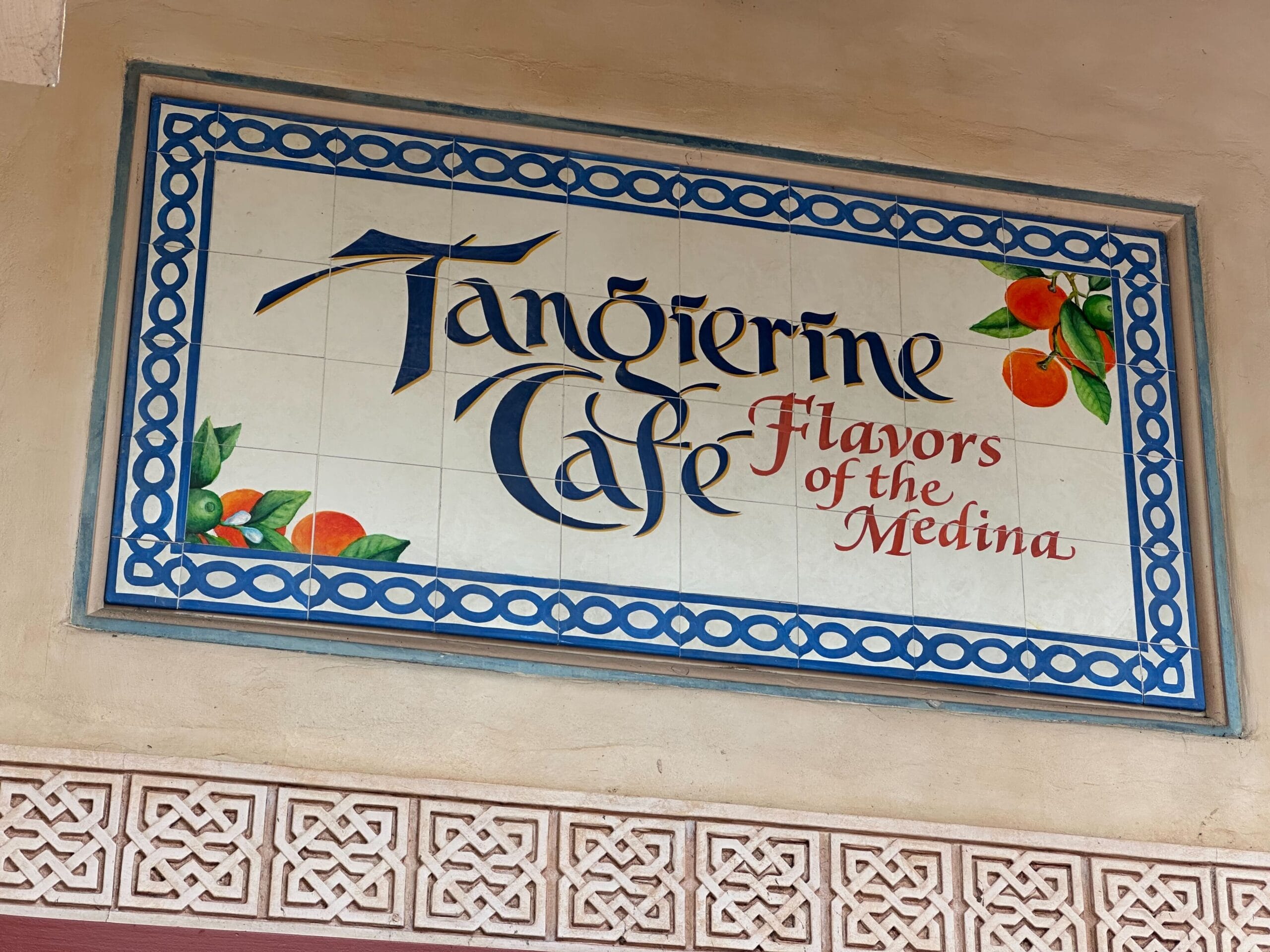 Tile sign reading "Tangerine Cafe: Flavors of the Medina," adorned with decorative oranges and a blue border design, perfectly captures the spirit of the Flower & Garden Festival.