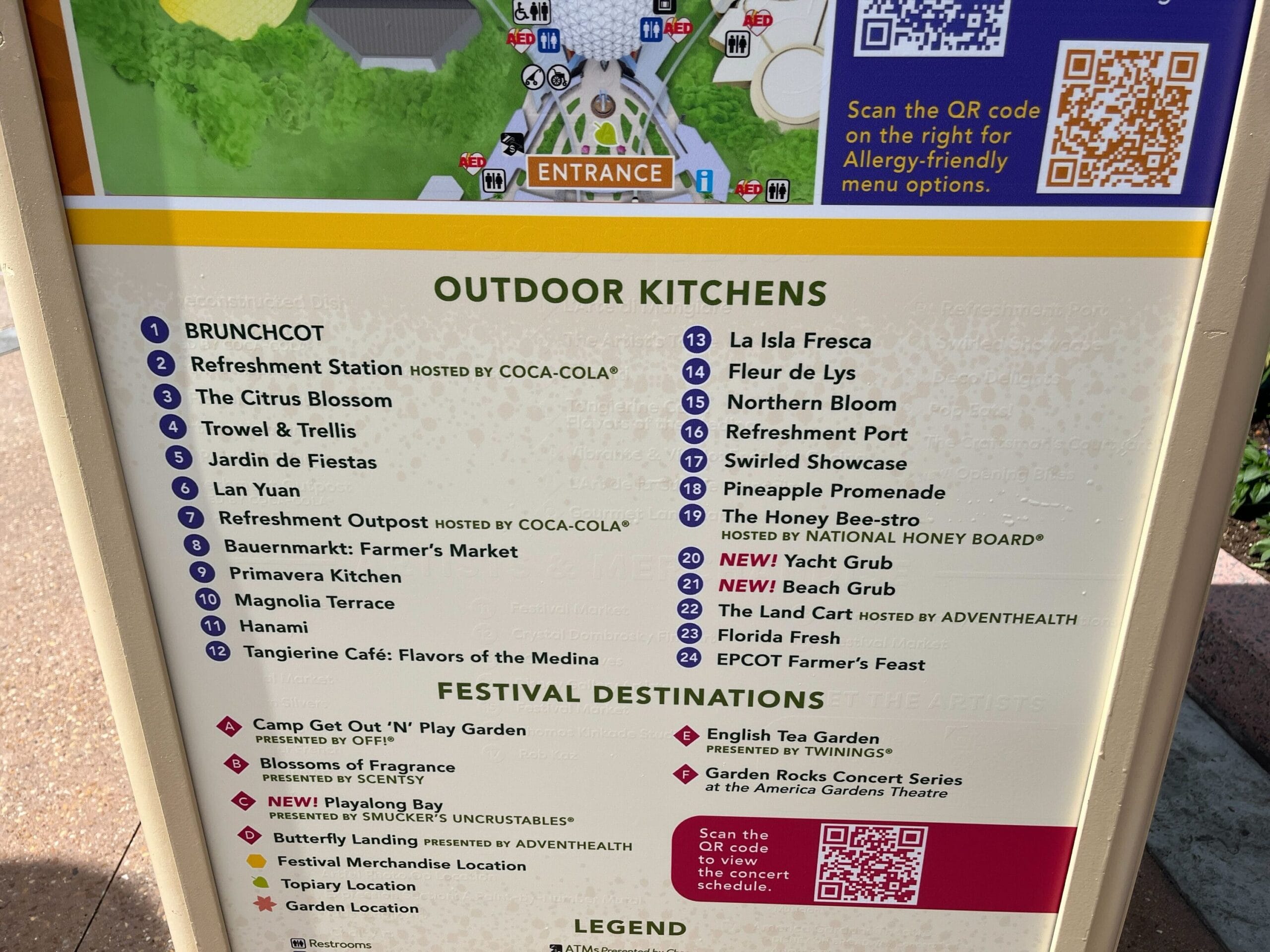 Sign with a list of outdoor kitchens and festival destinations at the 2025 Flower & Garden Festival in EPCOT, featuring names like "Brunchcot" and "La Isla Fresca," complete with a QR code for allergy-friendly menu options.