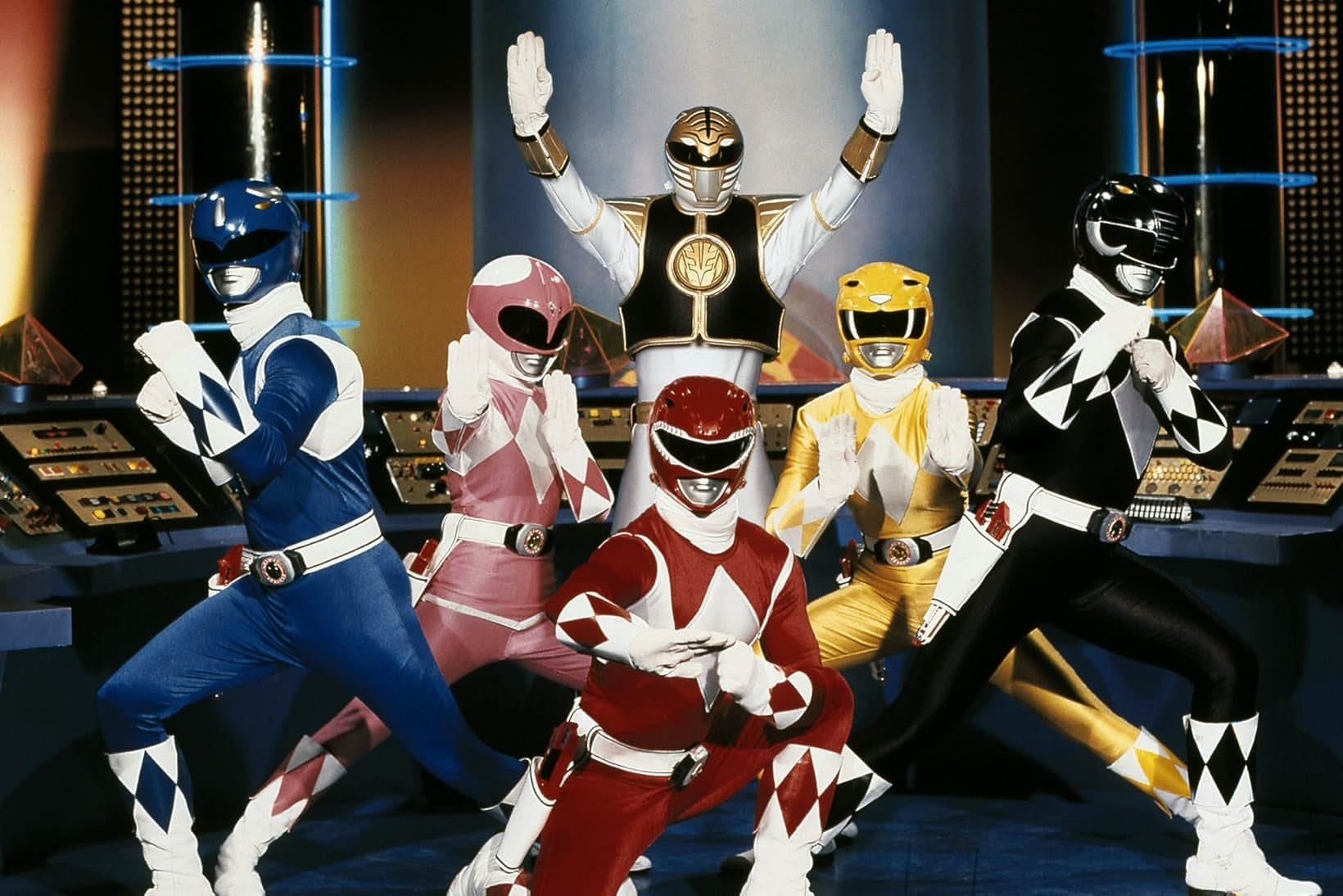 Six colorful, costumed superheroes, reminiscent of the Power Rangers, strike dynamic action poses in a high-tech control room. Their vibrant uniforms and daring stances make them look straight out of an exciting Disney+ series.