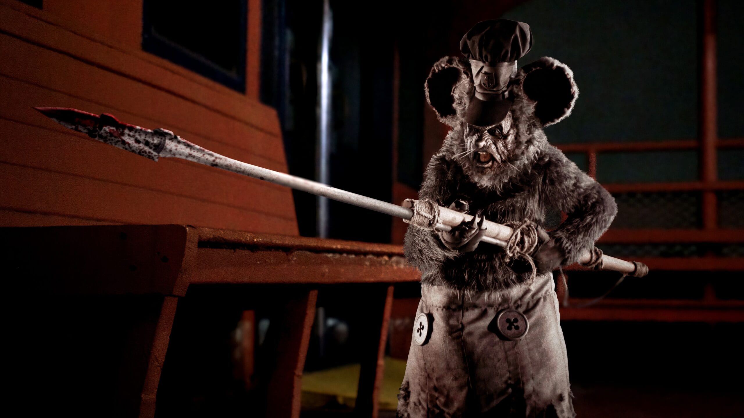 A character in a detailed rat costume holding a long spear, standing in a dimly lit setting.