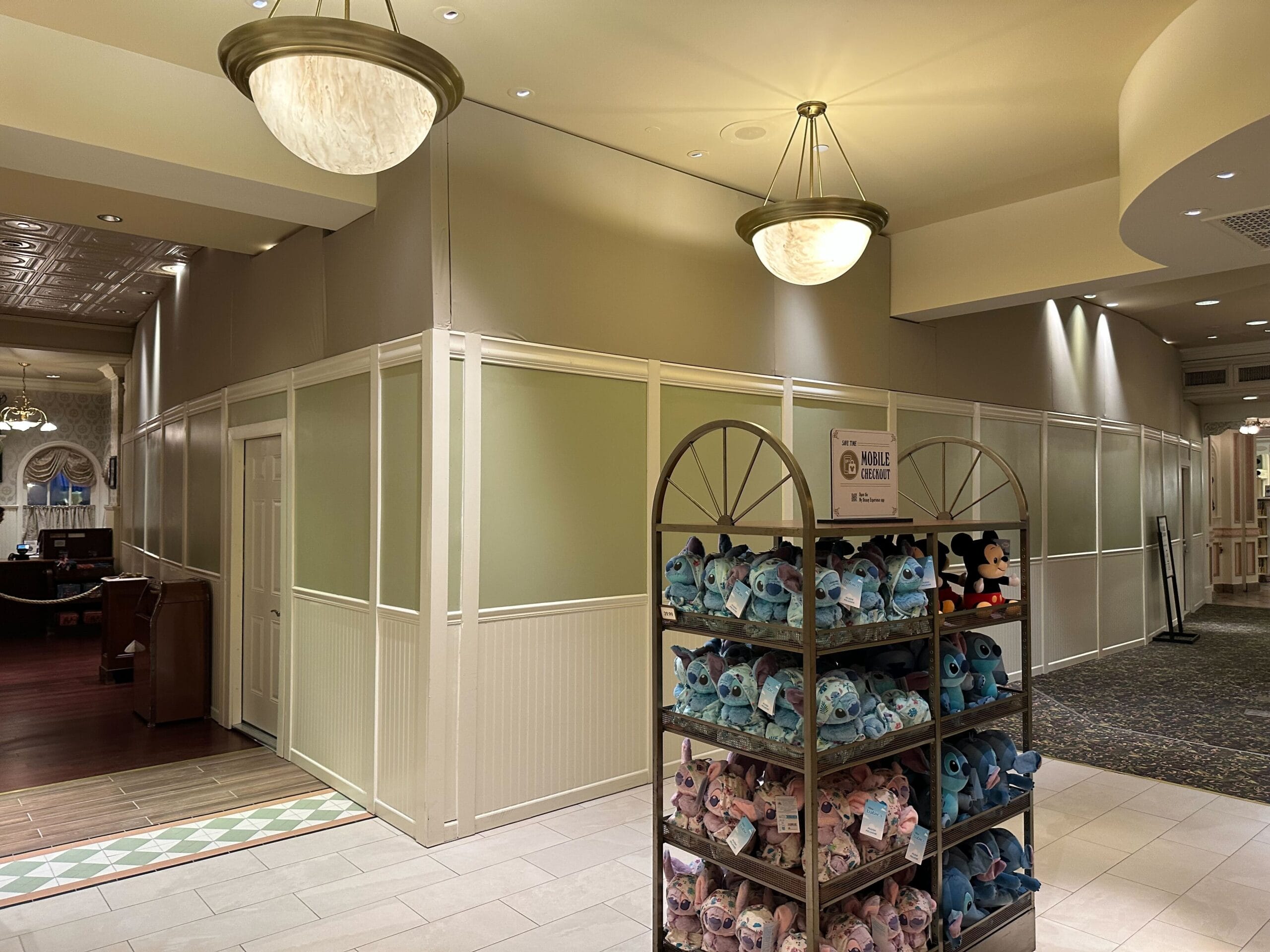 A store interior with a partitioned off area, plush toys on a rack in the foreground, and two large ceiling lights visible.