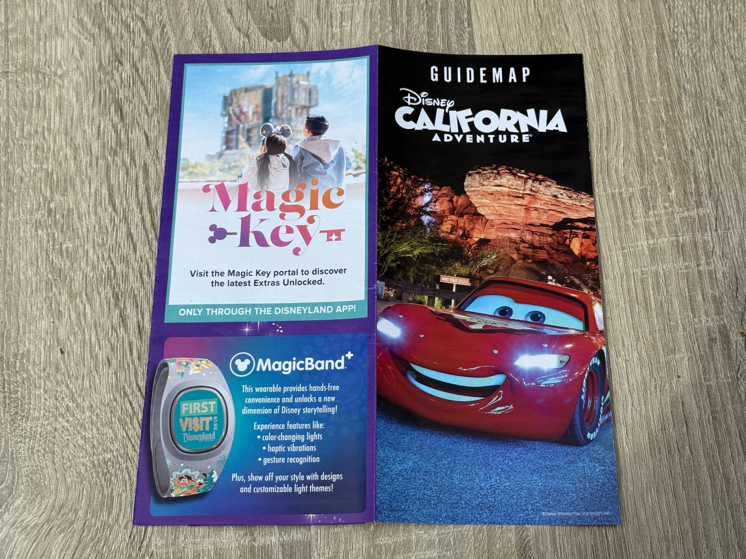 Disney California Adventure guidemap with Lightning McQueen and Magic Key info on a wooden Disneyland Resort table.