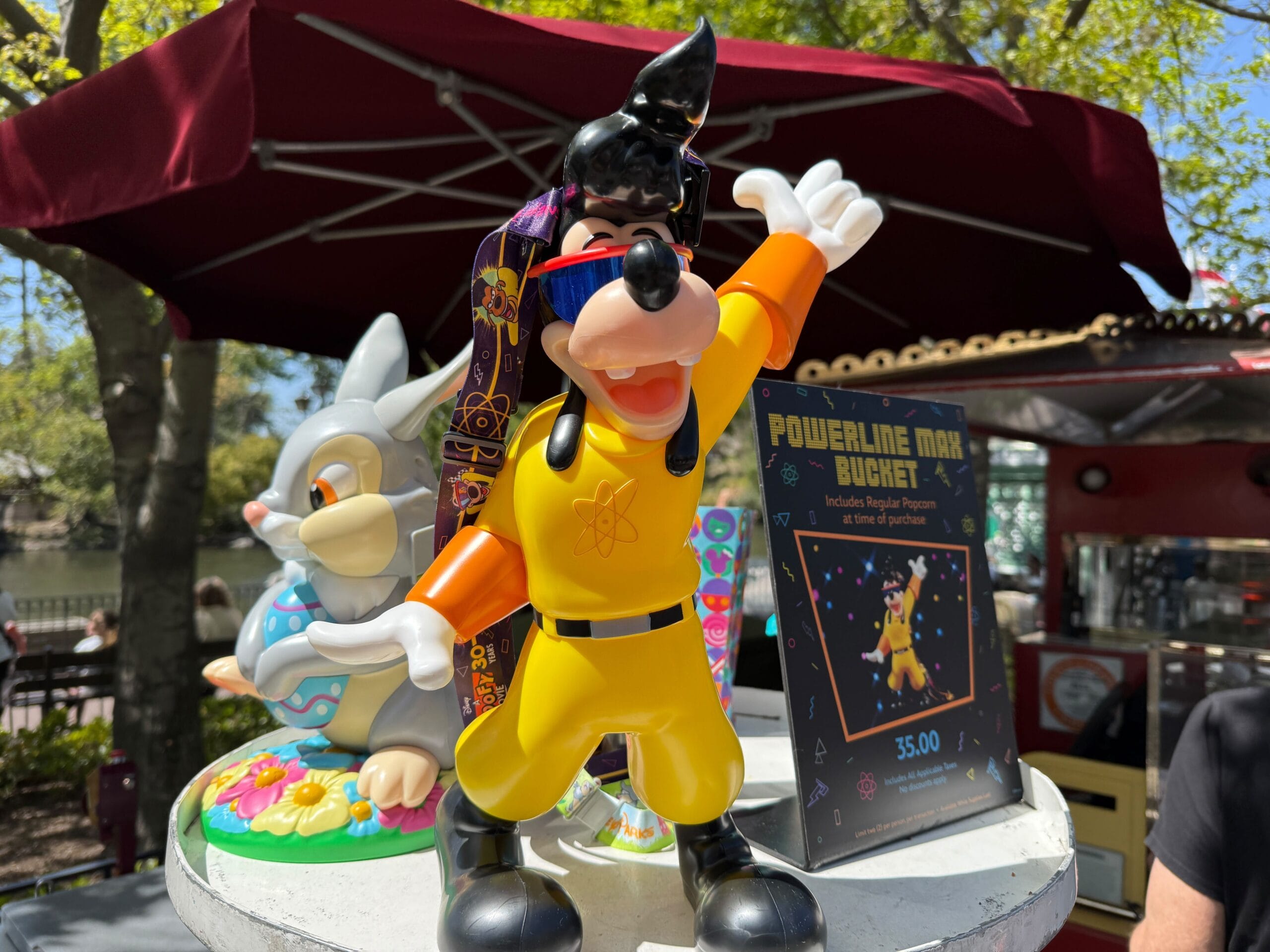 A Powerline Max popcorn bucket from Disneyland is displayed on a table, accompanied by a promotional sign.