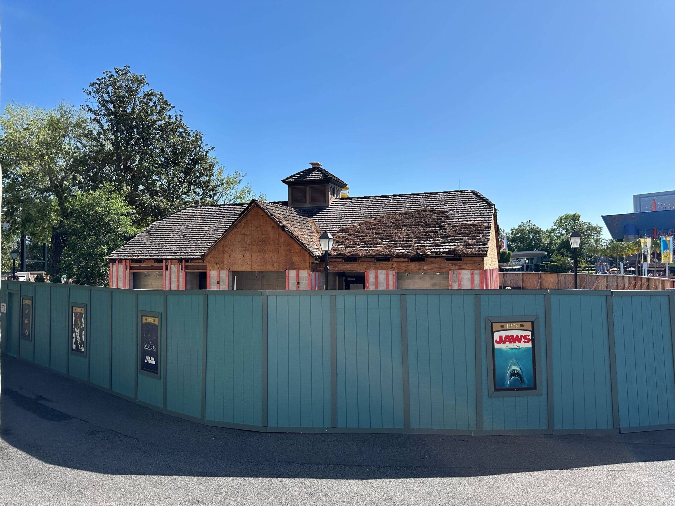 A building under construction behind a blue temporary fence with movie posters, including "Jaws," attached.