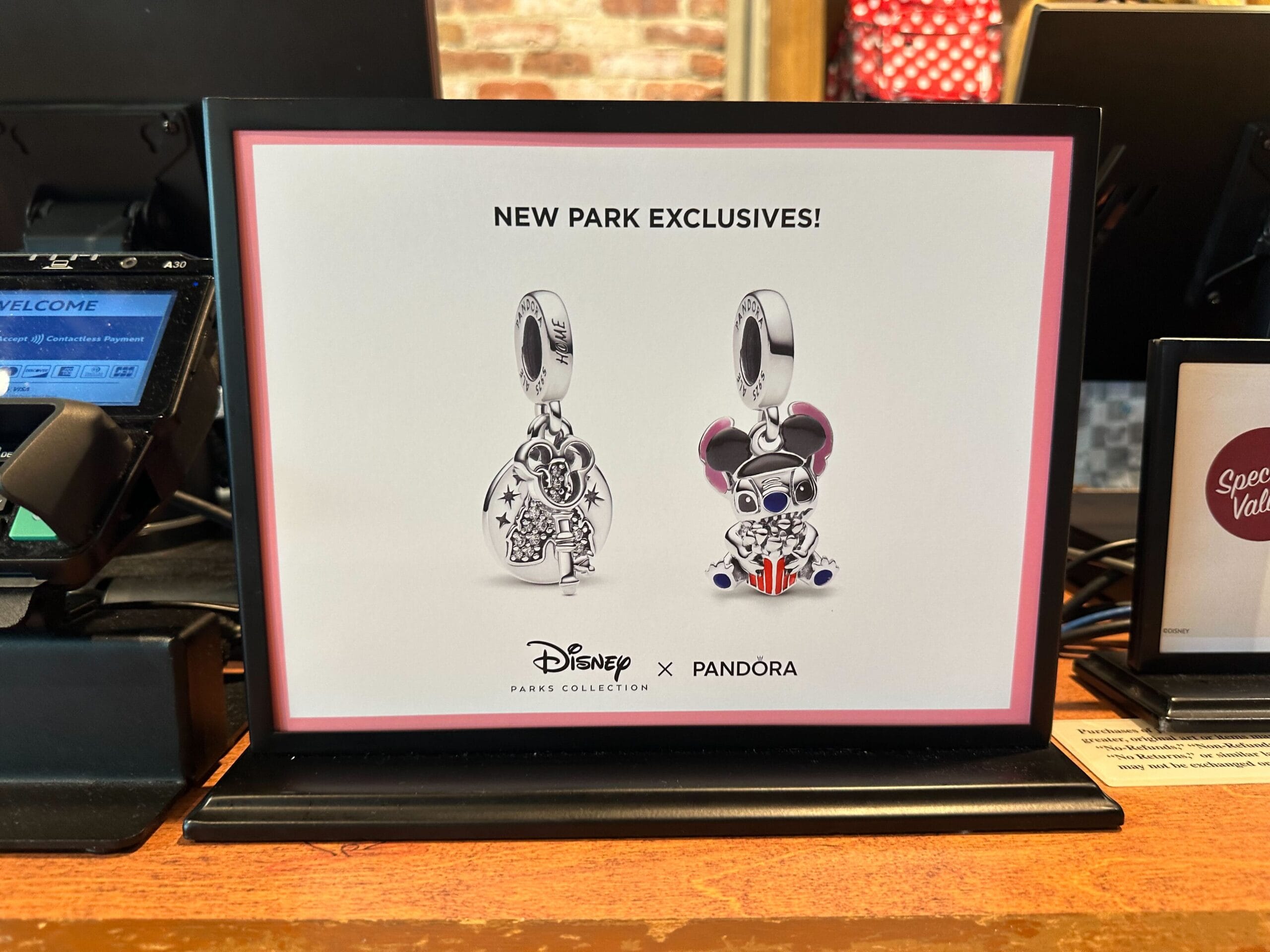 Introducing the latest additions to the Pandora Charms collection: a display stand showcasing two Disney x Pandora exclusives. One charm boasts a castle design, while the other features Mickey Mouse sporting sunglasses with a Union Jack touch. Perfect for collectors!.