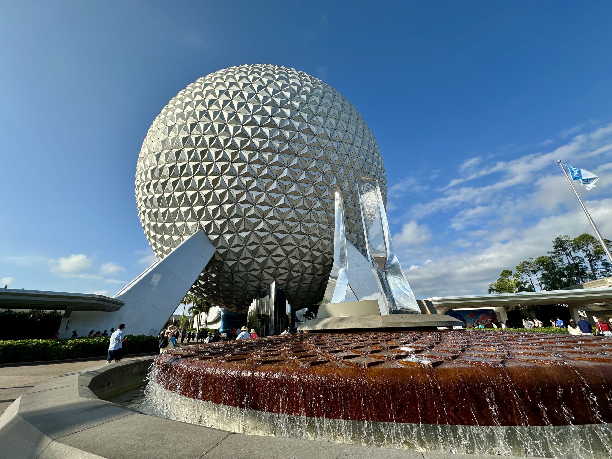 A large geodesic sphere with a fountain in front at EPCOT, Walt Disney World, on a sunny day.