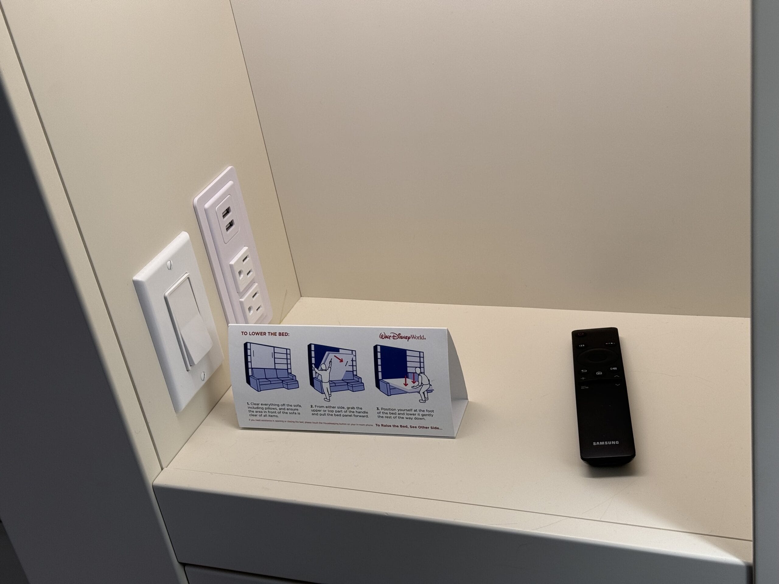 Remodeled desk in the 1-Bedroom Villa features a light switch, power outlets, remote control, and a card with illustrations and instructions, capturing the charm of Disney's Hilton Head Island Resort.