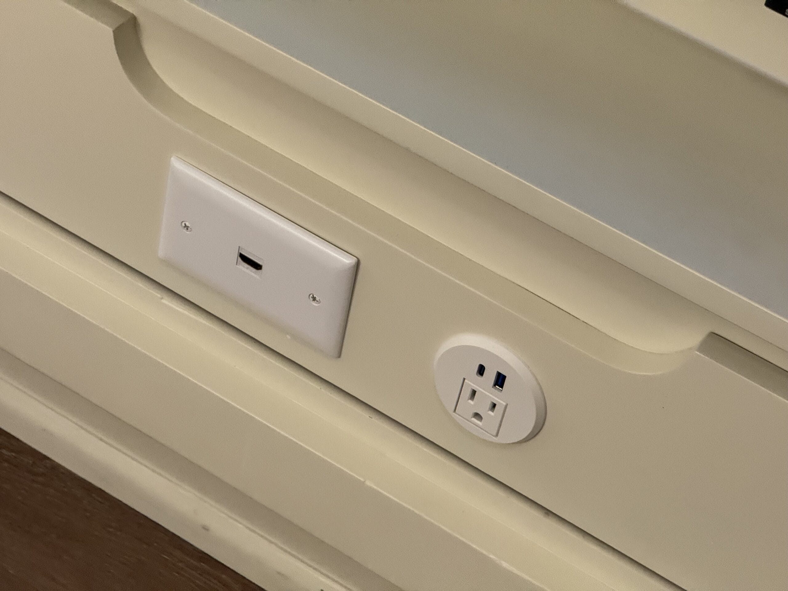 In a remodeled villa at Disney's Hilton Head Island Resort, a wall outlet featuring a round electrical socket and USB ports sits neatly beside a blank white wall plate on the smooth beige surface.