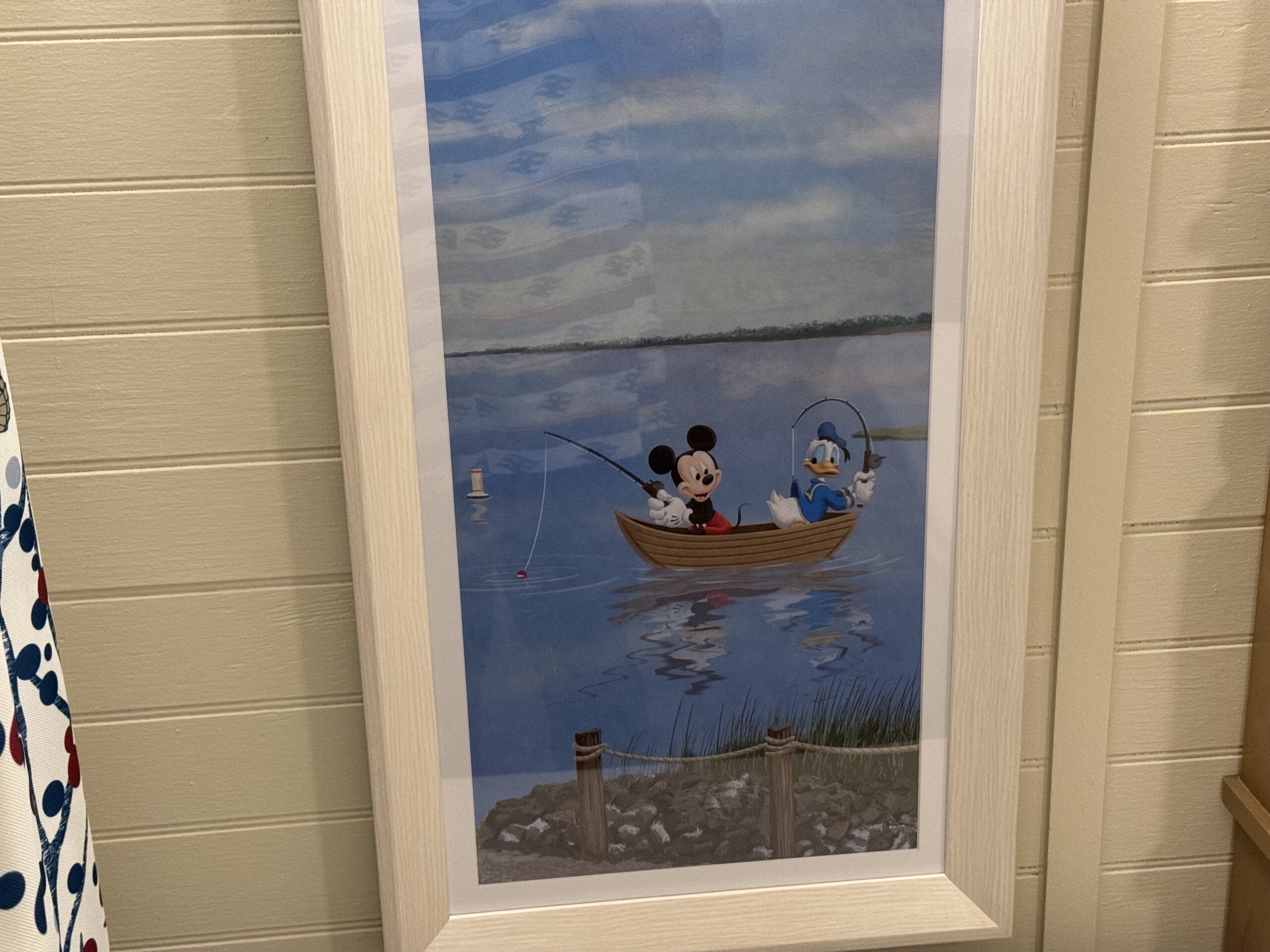 Framed artwork of two animated characters enjoying a relaxed day at Disney's Hilton Head Island Resort, fishing in a boat on the tranquil lake, with one character holding a fishing rod and another skillfully steering.