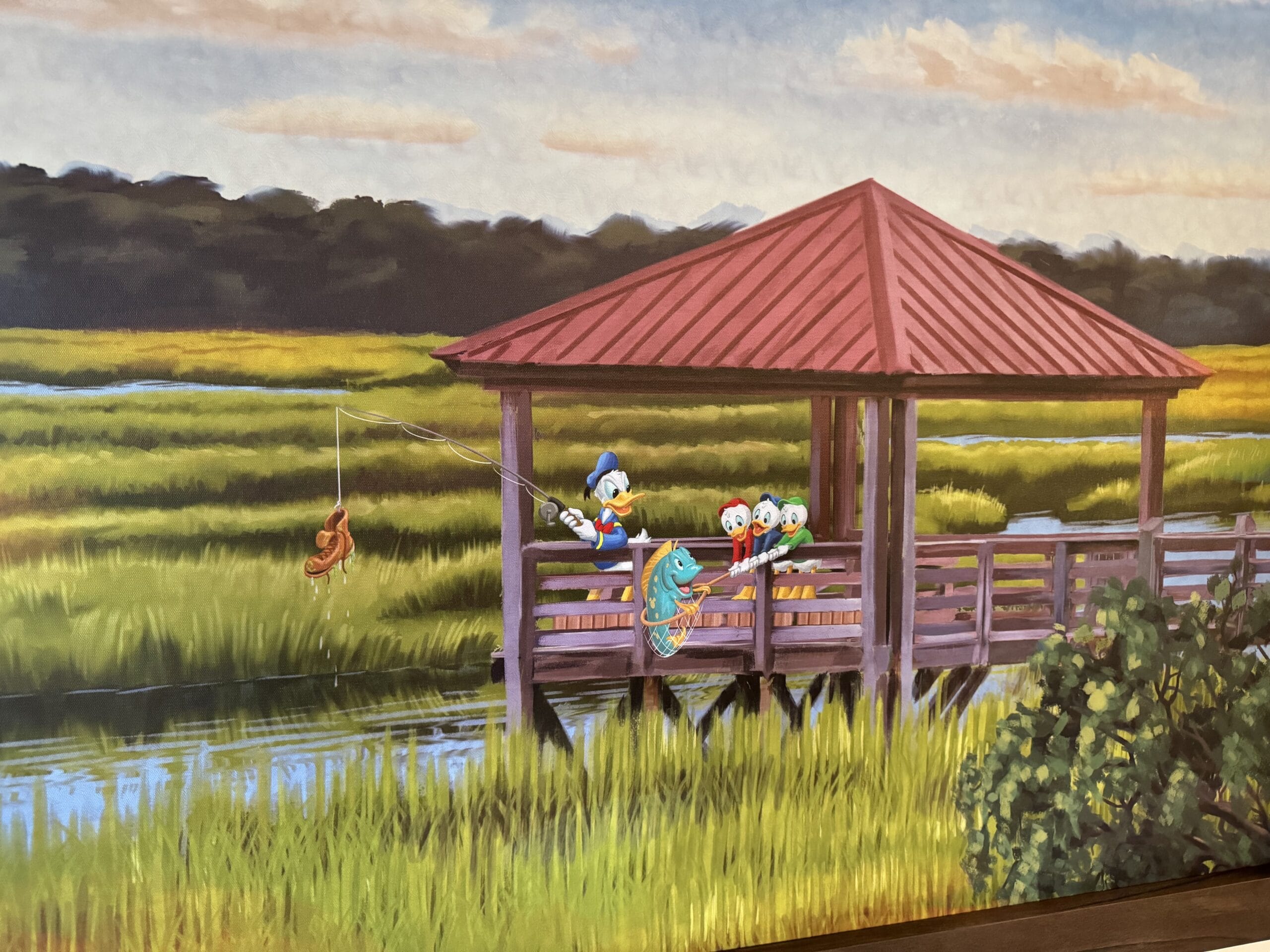 At Disney's Hilton Head Island Resort, a cartoon family enjoys their tour, fishing from a wooden gazebo with a red roof over the marsh. One character excitedly holds a rod with a fish on the line, while others watch from their remodeled 1-bedroom villa nearby.