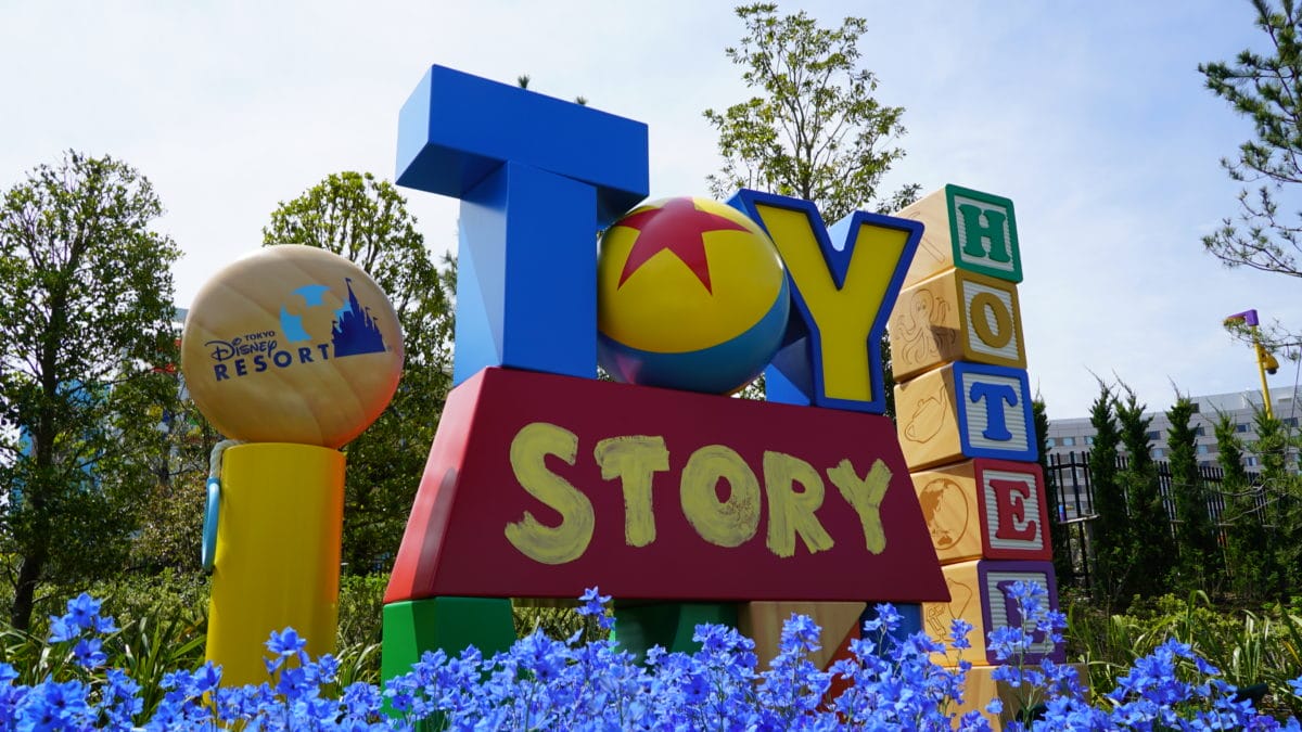 Colorful "Toy Story Hotel" sign near the Fantasy Springs entrance, with playful letters, flowers, and lush greenery.