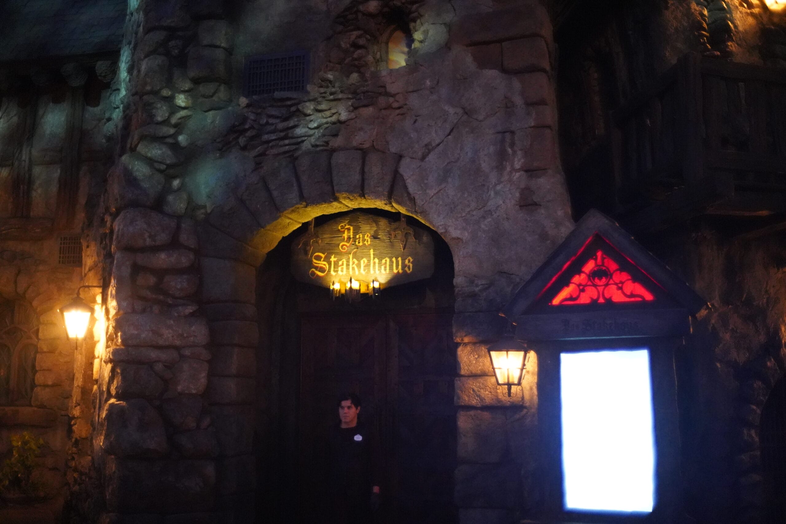 A dimly lit stone building at night with a glowing "Das Stakehaus" sign above the wooden door.