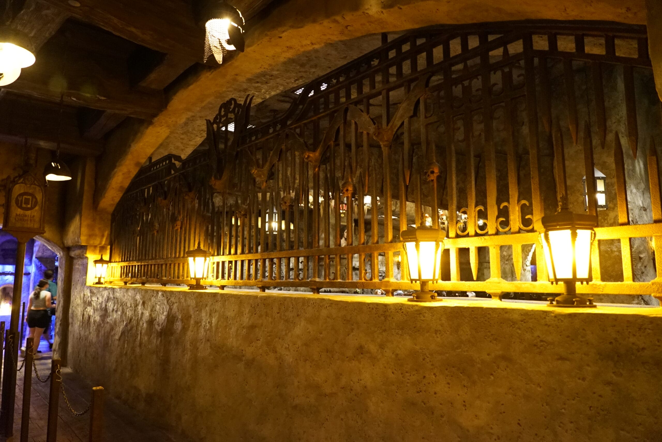 Dimly lit stone corridor with an iron gate and lanterns, evoking the eerie ambiance of Das Stakehaus.