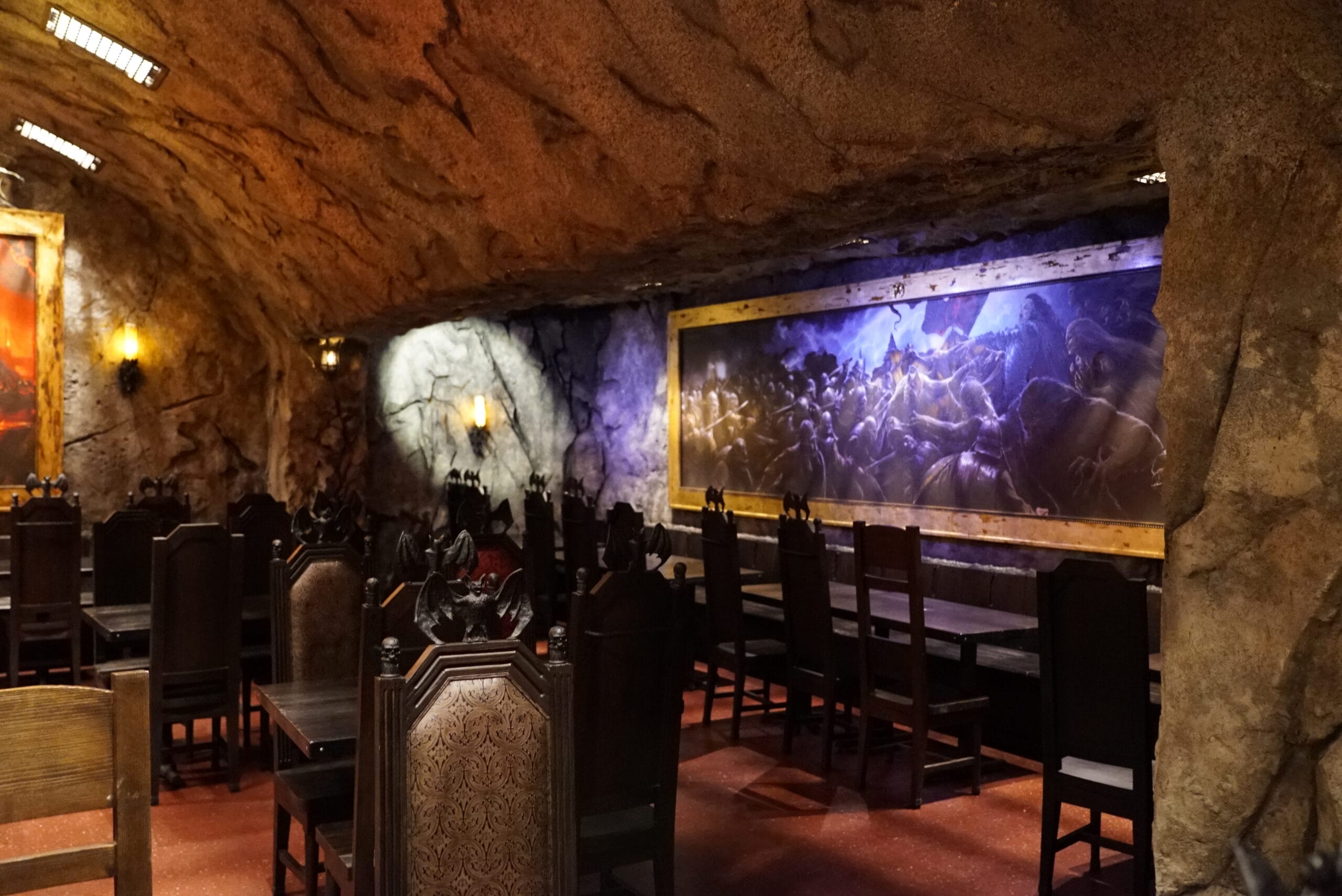 Das Stakehaus is a dimly lit, cave-themed restaurant with dark wood chairs and a large mural on the stone wall.