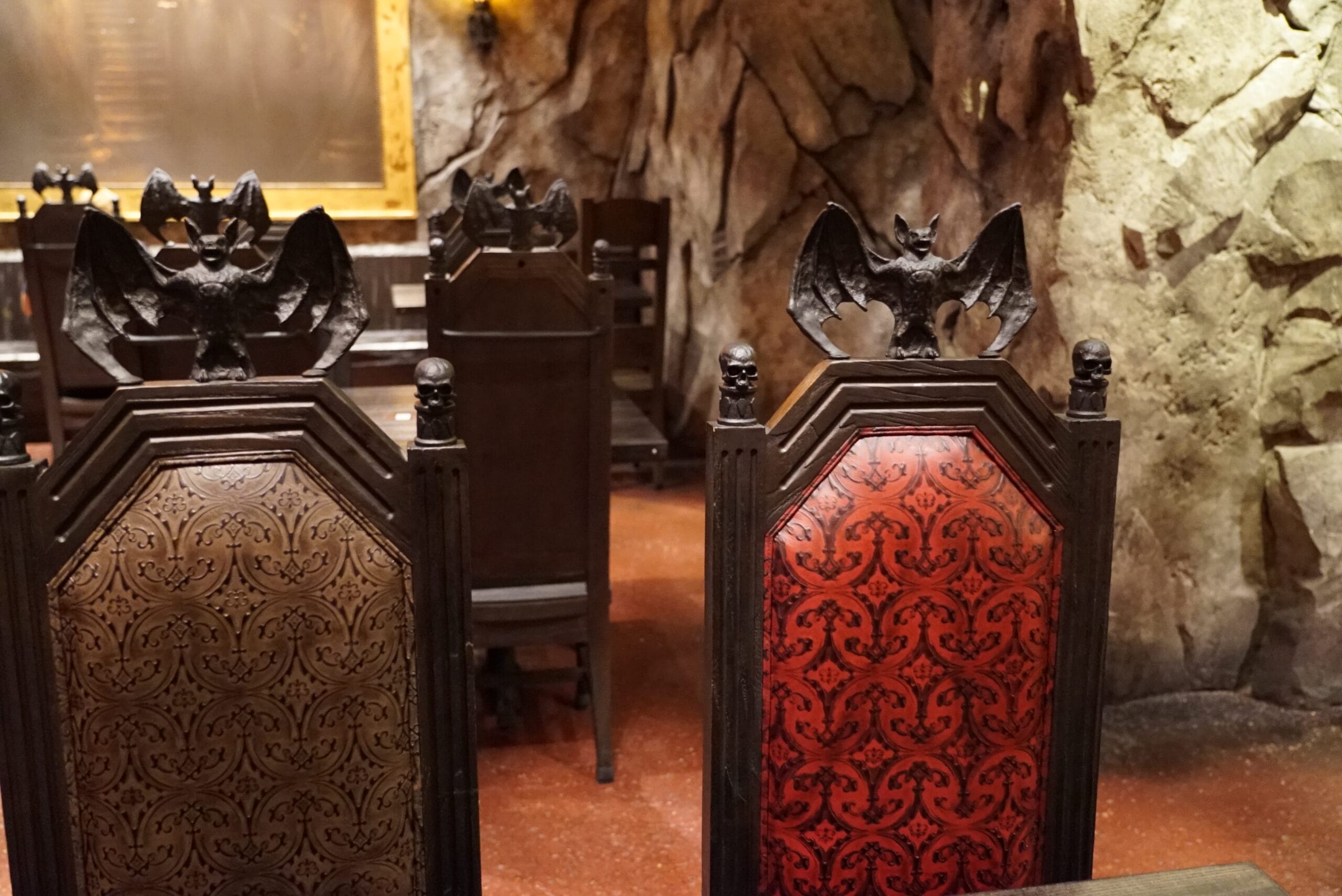 Das Stakehaus ornate wooden chairs with bat-shaped carvings and patterned upholstery, set against a cave-like wall.