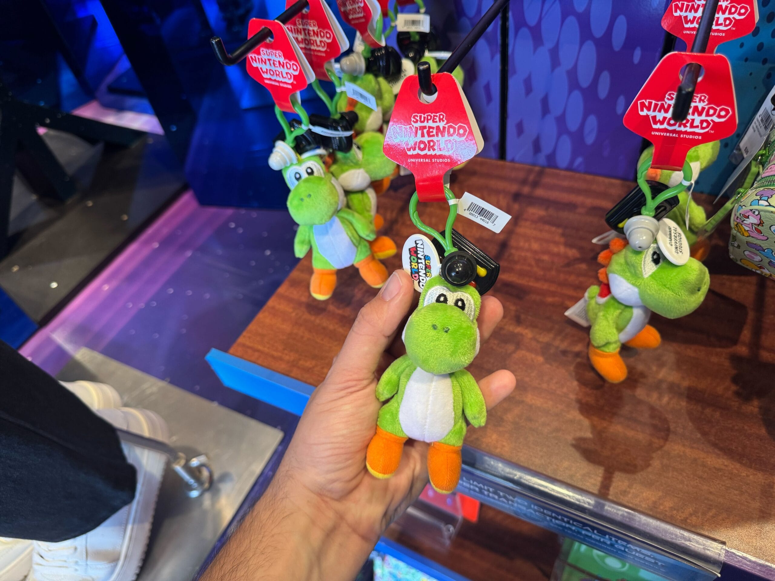 A hand holds a small Yoshi plush keychain, perfect Yoshi merchandise from Universal Studios Hollywood.
