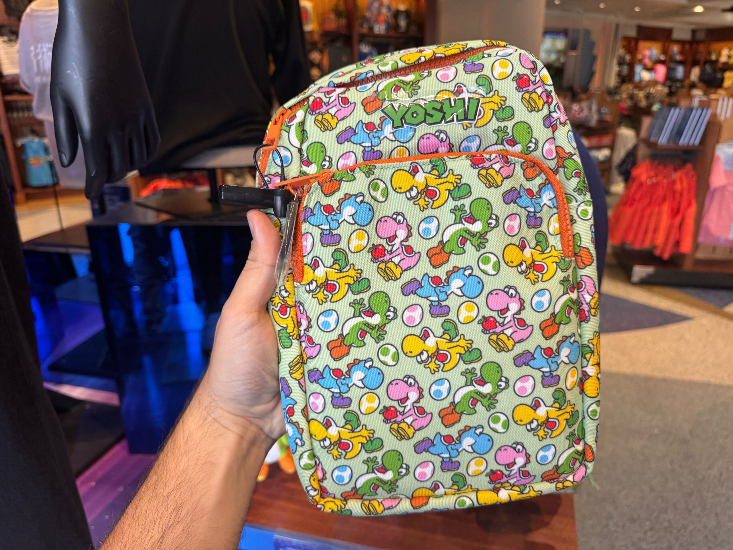 A hand holds Yoshi merchandise with a colorful cartoon pattern at Universal Studios Hollywood.