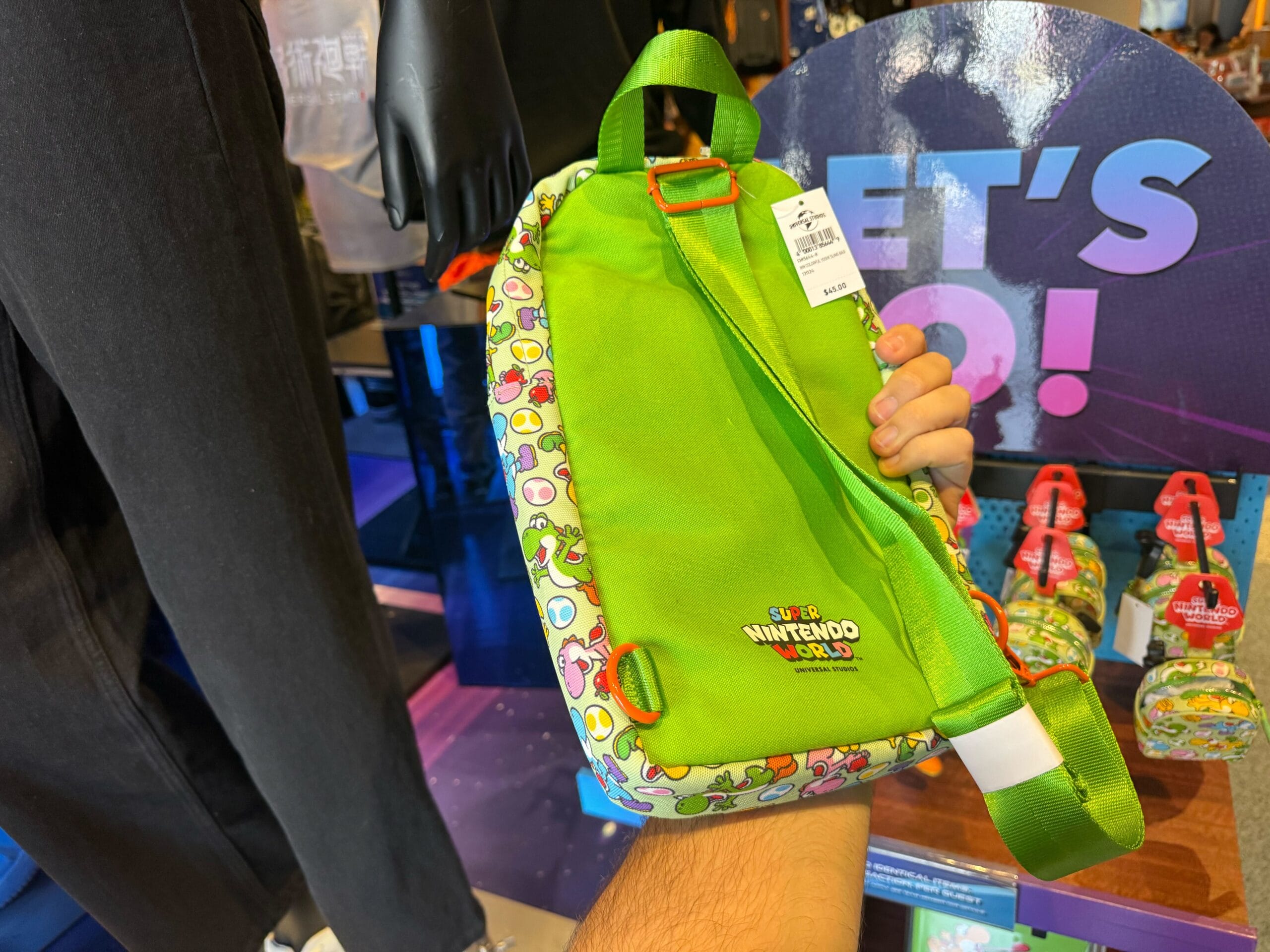 A green Super Nintendo World bag with Yoshi print is held up at Universal Studios Hollywood.