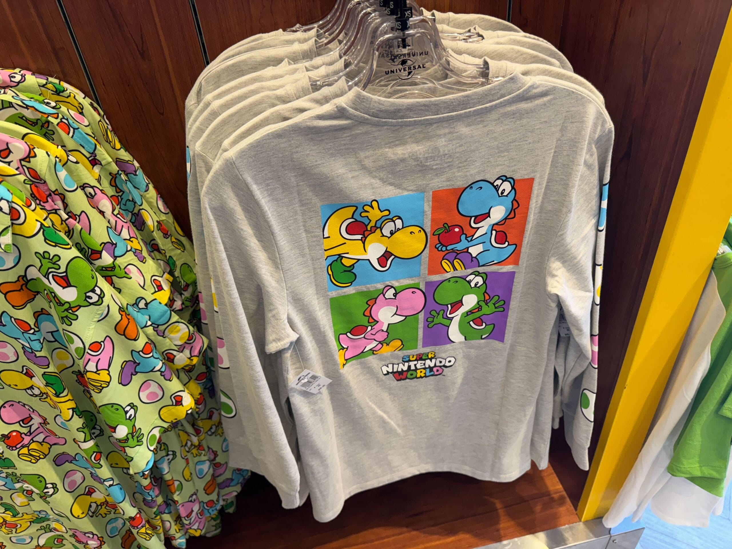 Gray long-sleeve Yoshi merchandise with “Super Nintendo World” logo, spotted at Universal Studios Hollywood store display.