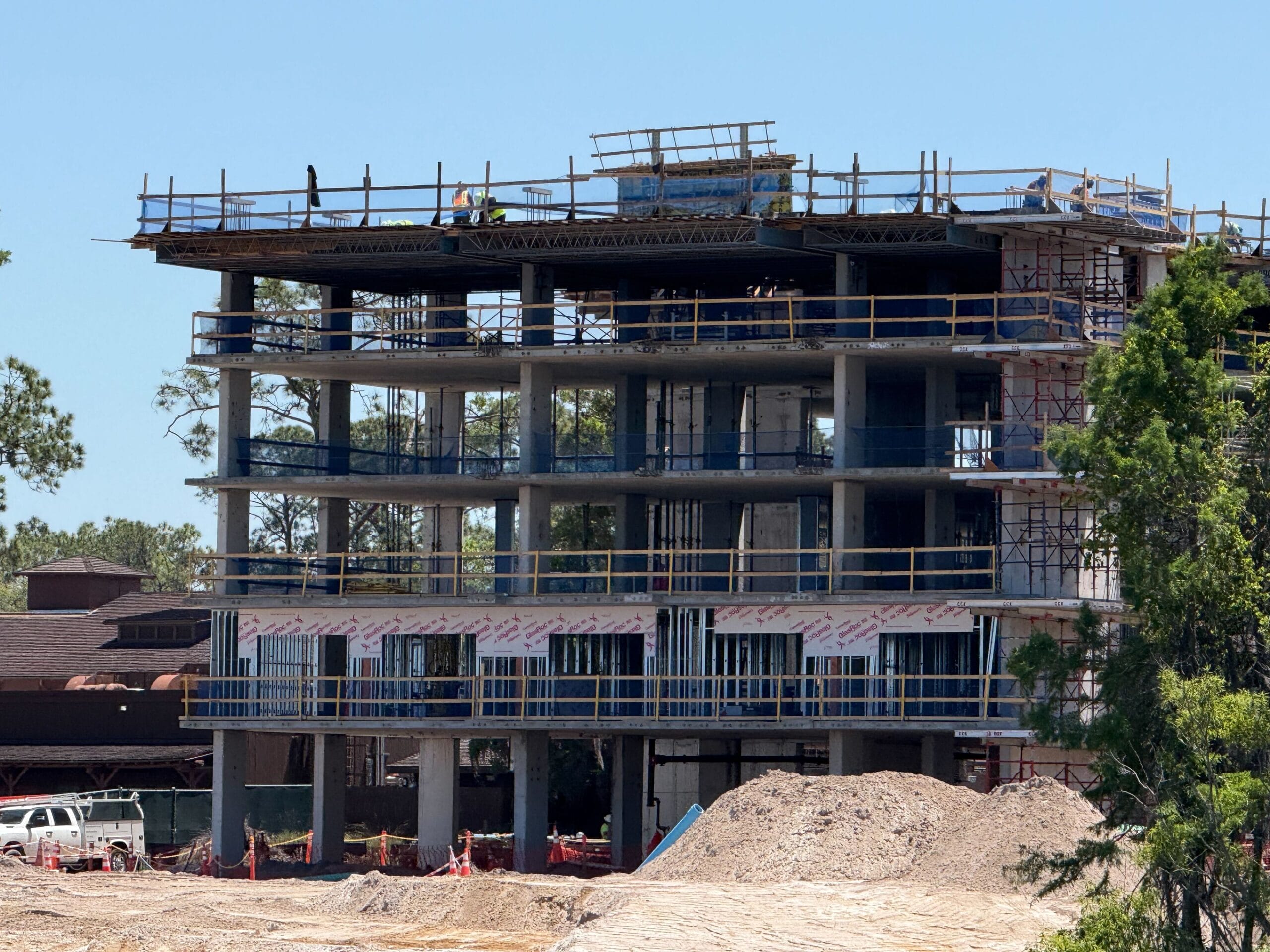 A multi-story building expansion with scaffolding and workers adding new floors on a sunny day.